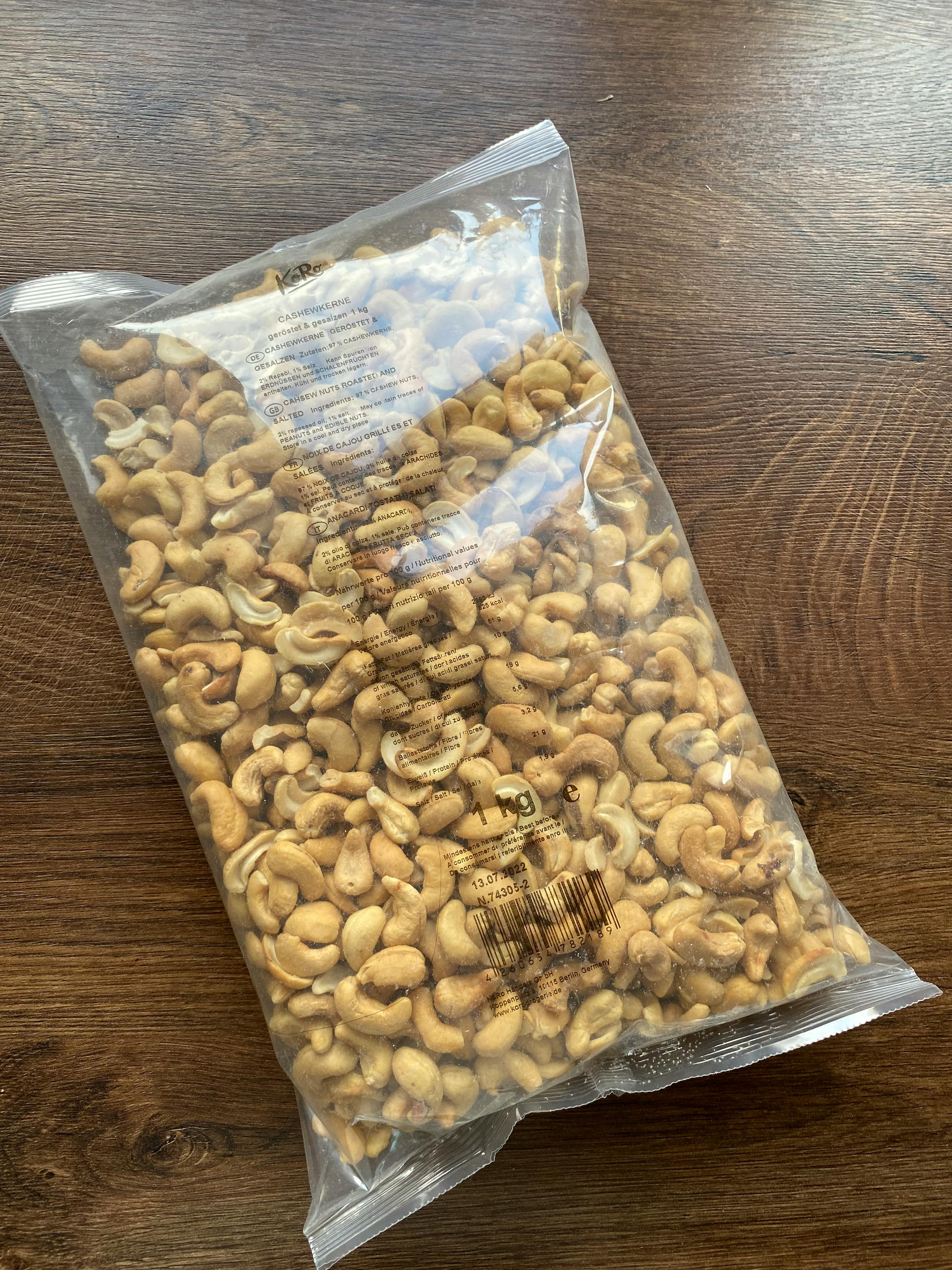 eine Plastiktüte mit gerösteten Cashewnüssen liegt auf einem Holztisch