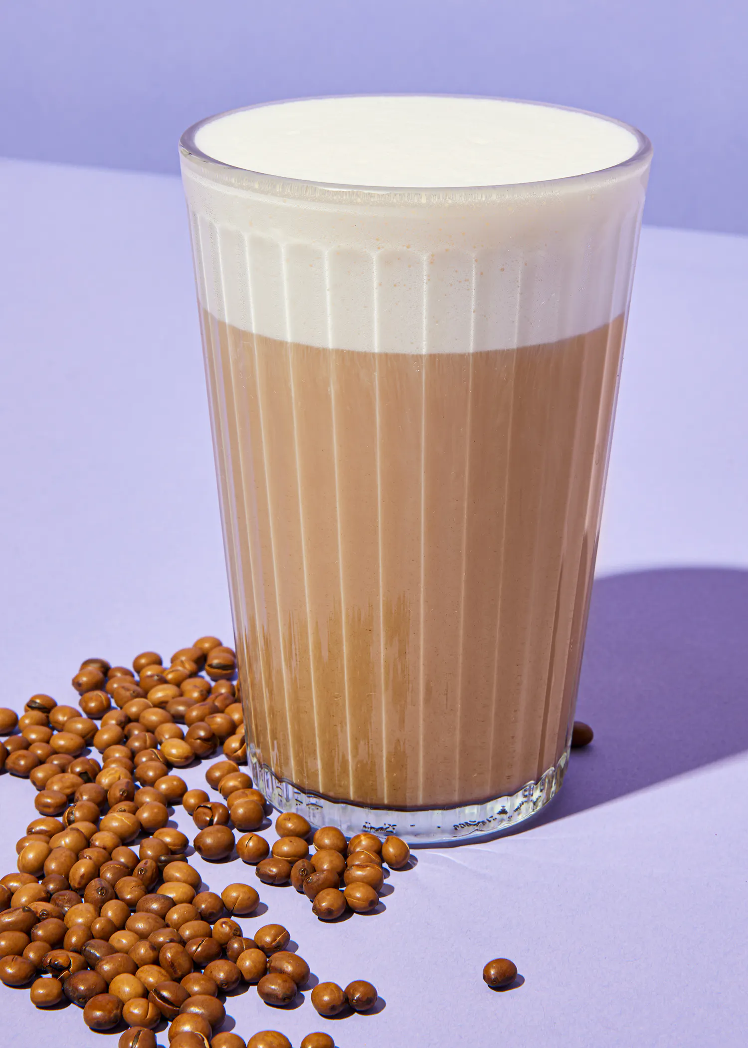 una taza de café está sobre una mesa junto a granos de café