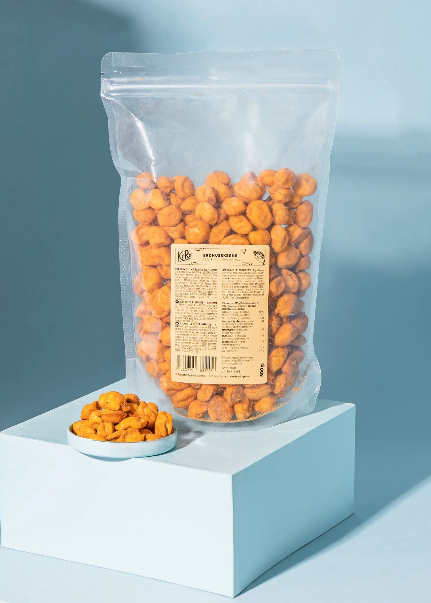 un sac de cacahuètes frites est assis sur une table blanche à côté d' une assiette de cacahuètes