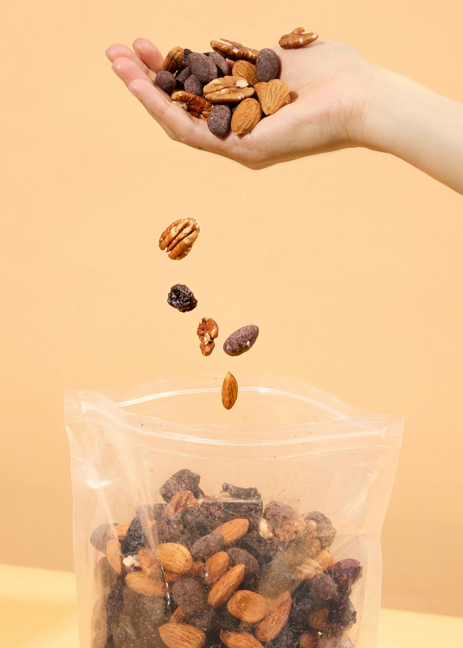 a hand holding a bag of nuts and raisins