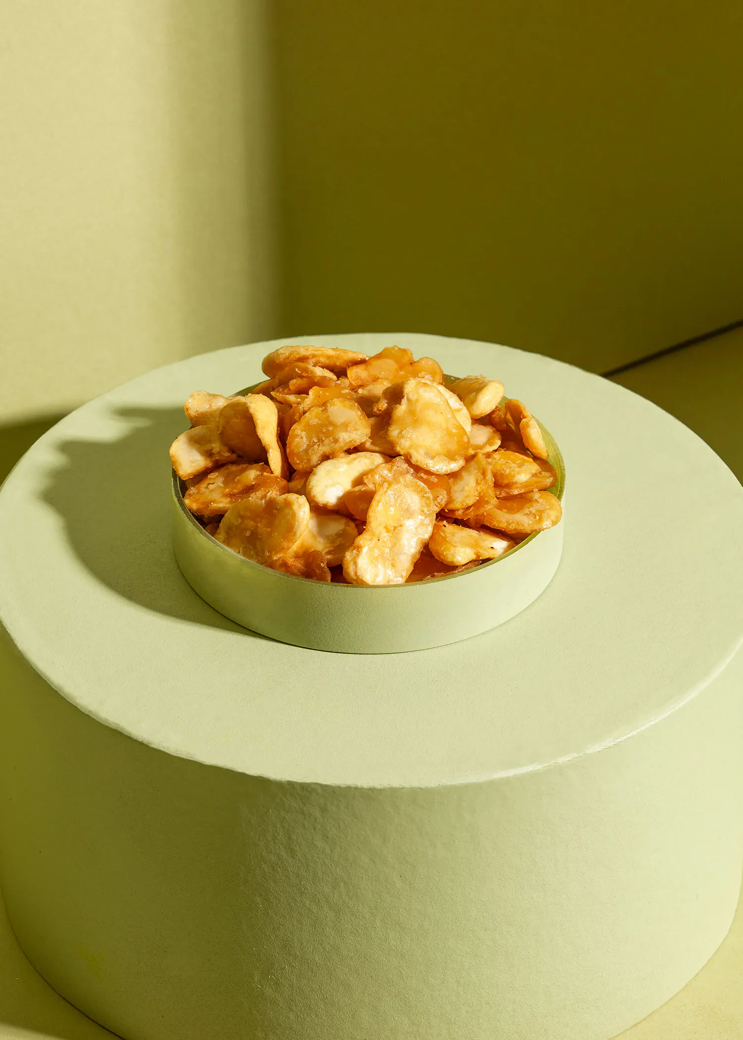un bol vert rempli de frites est assis sur une table verte