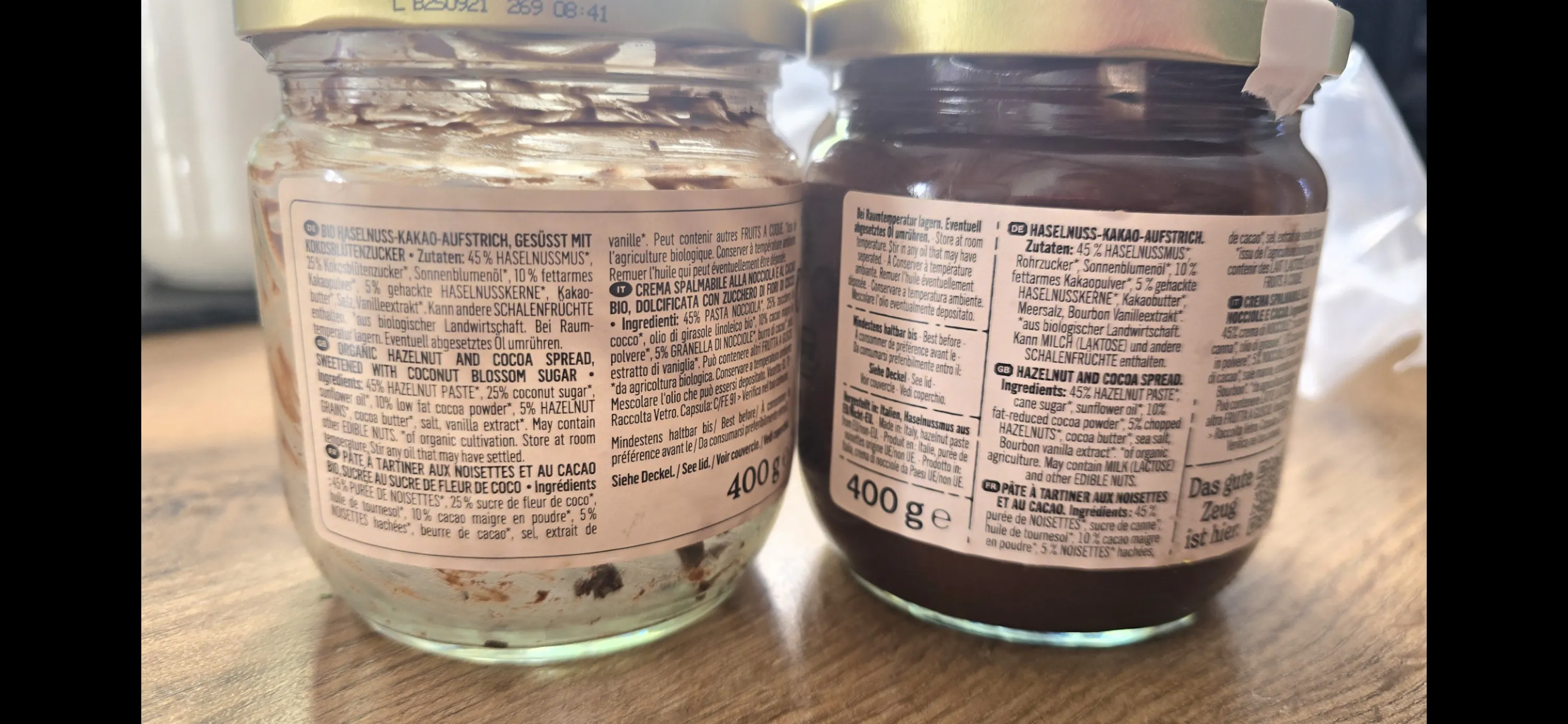 two glass jars of hazelnut cocoa spread, one nearly empty with light spread and the other full with dark spread, sit side-by-side with visible labels.