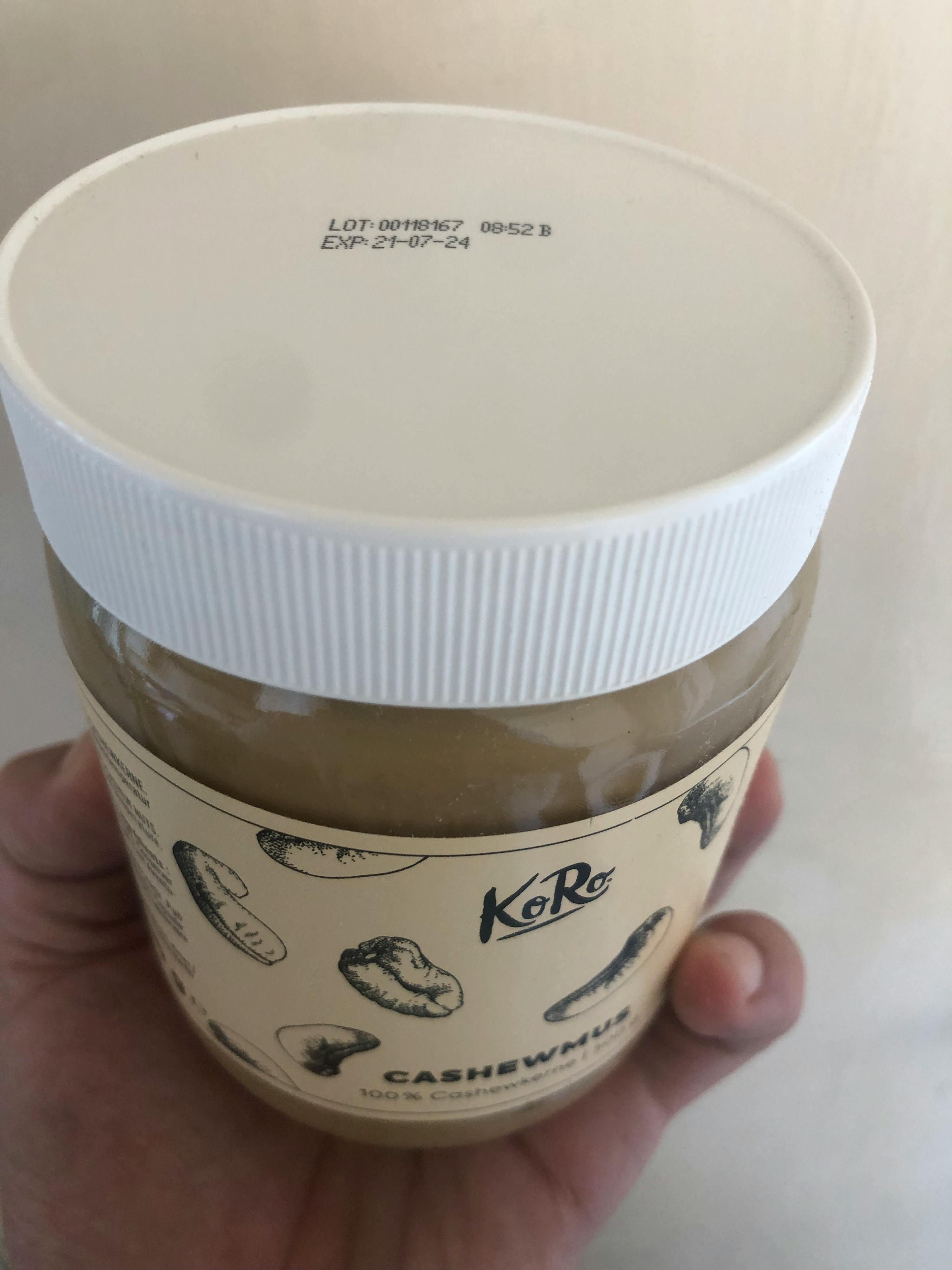 a person is holding a jar of cashew butter with expiration date printed on the lid