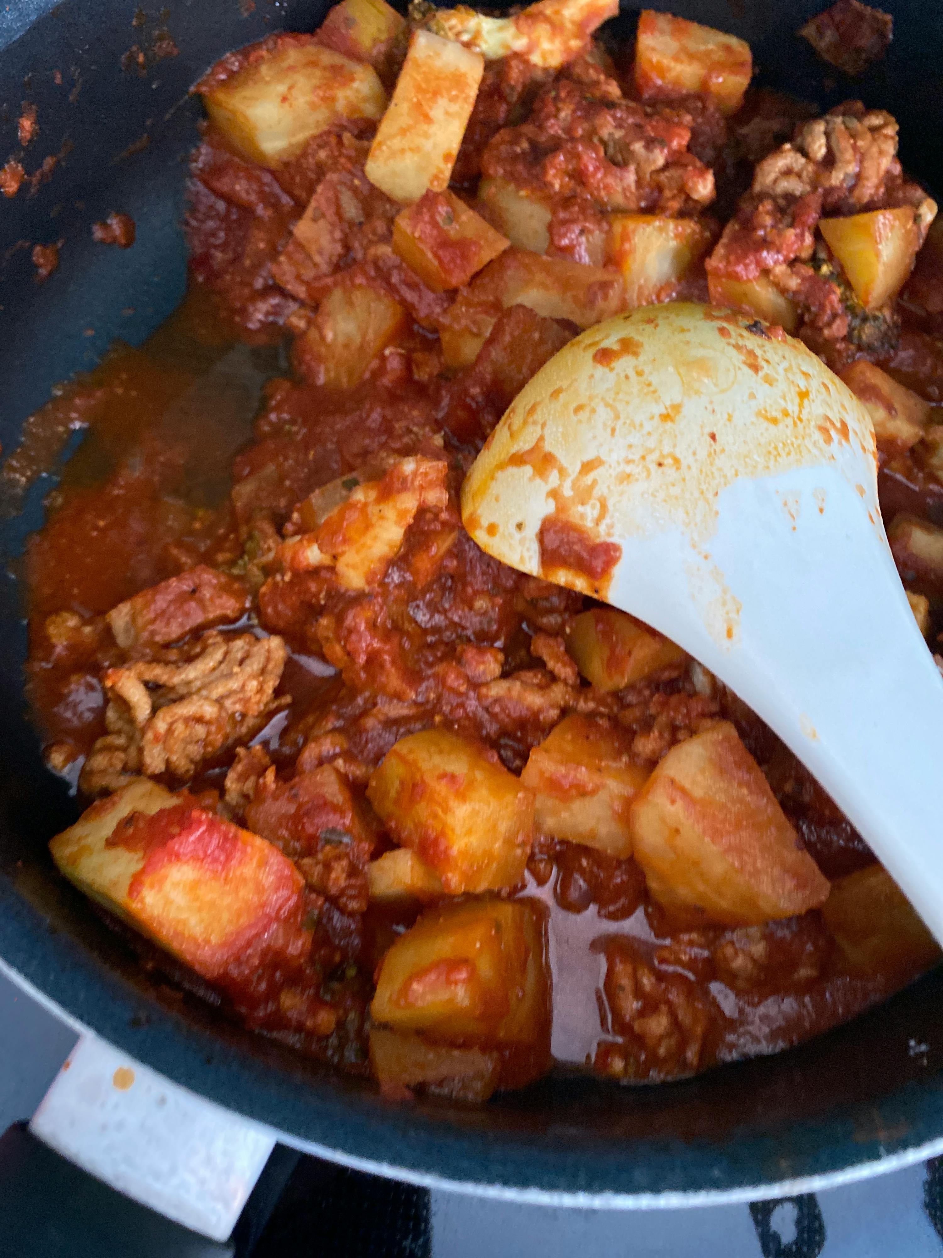 a white spoon is in a pot of stew