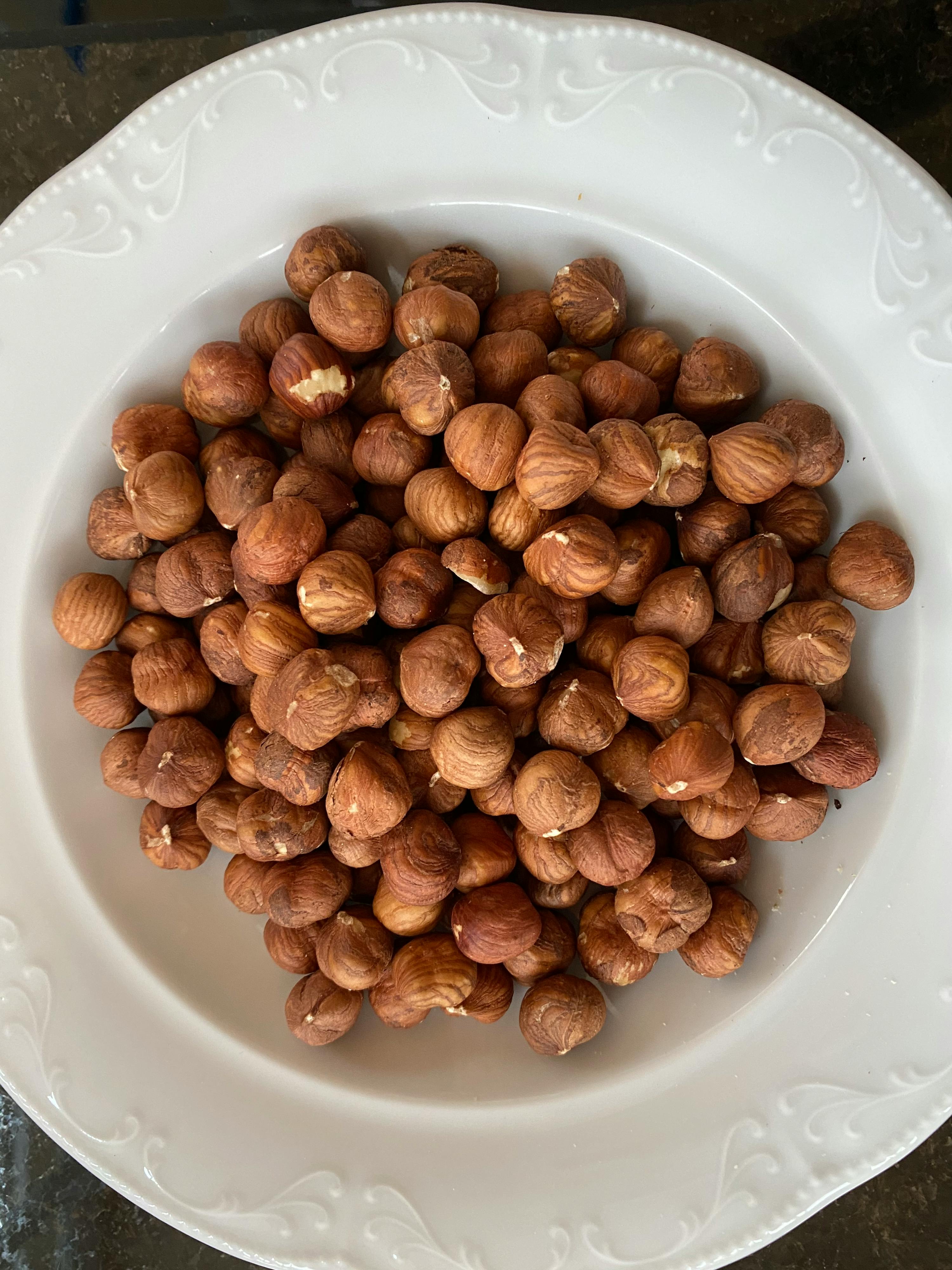 un piatto bianco pieno di nocciole su un tavolo