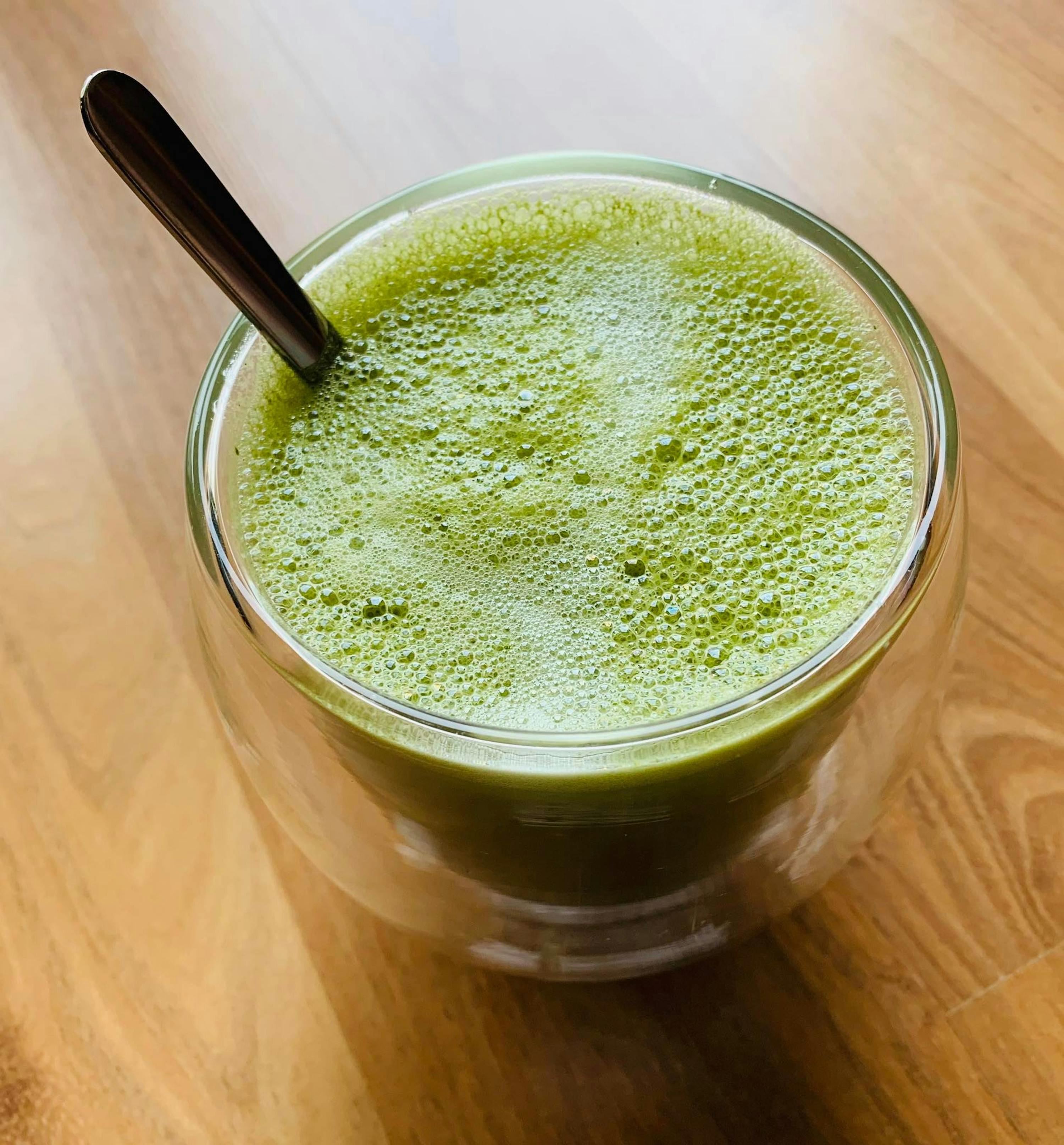 a cup of green liquid with a spoon in it