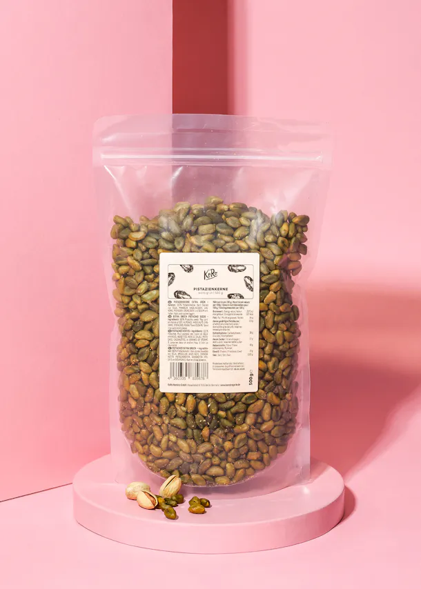 un sac de pistaches est assis sur une table rose