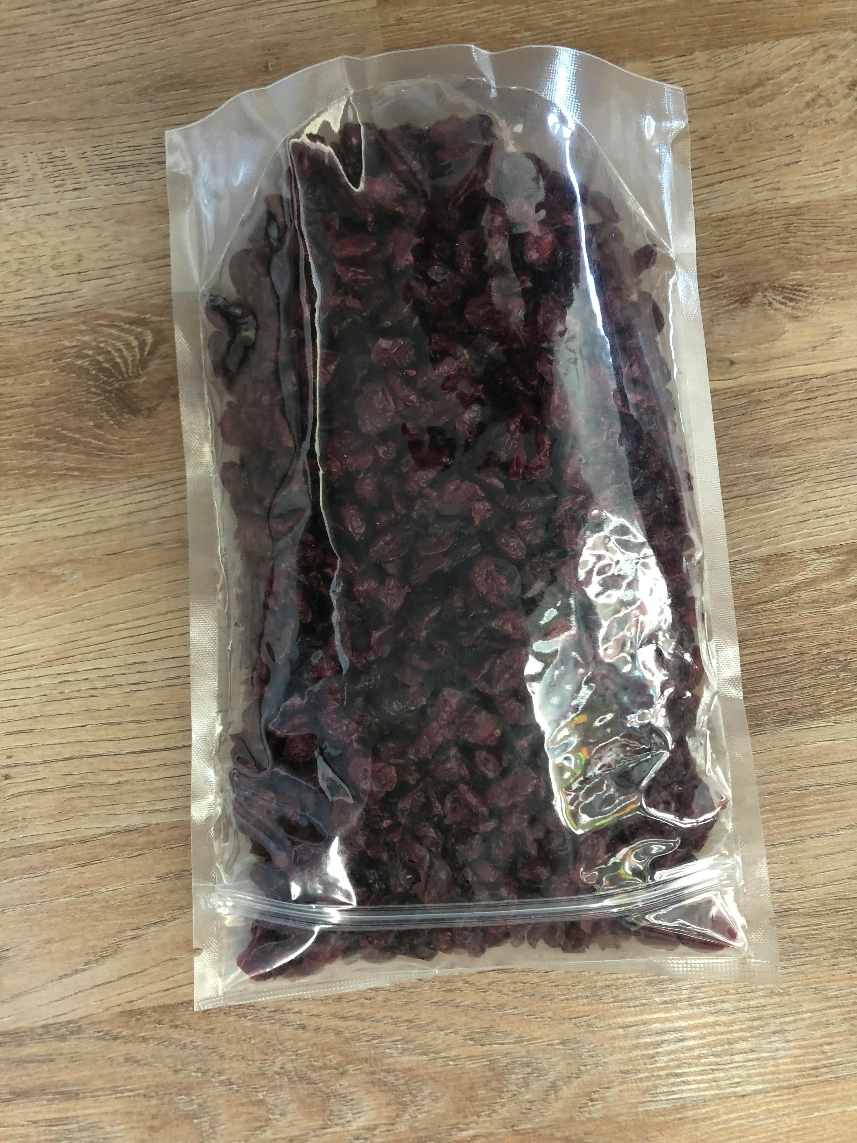 a bag of dried cranberries is sitting on a wooden table