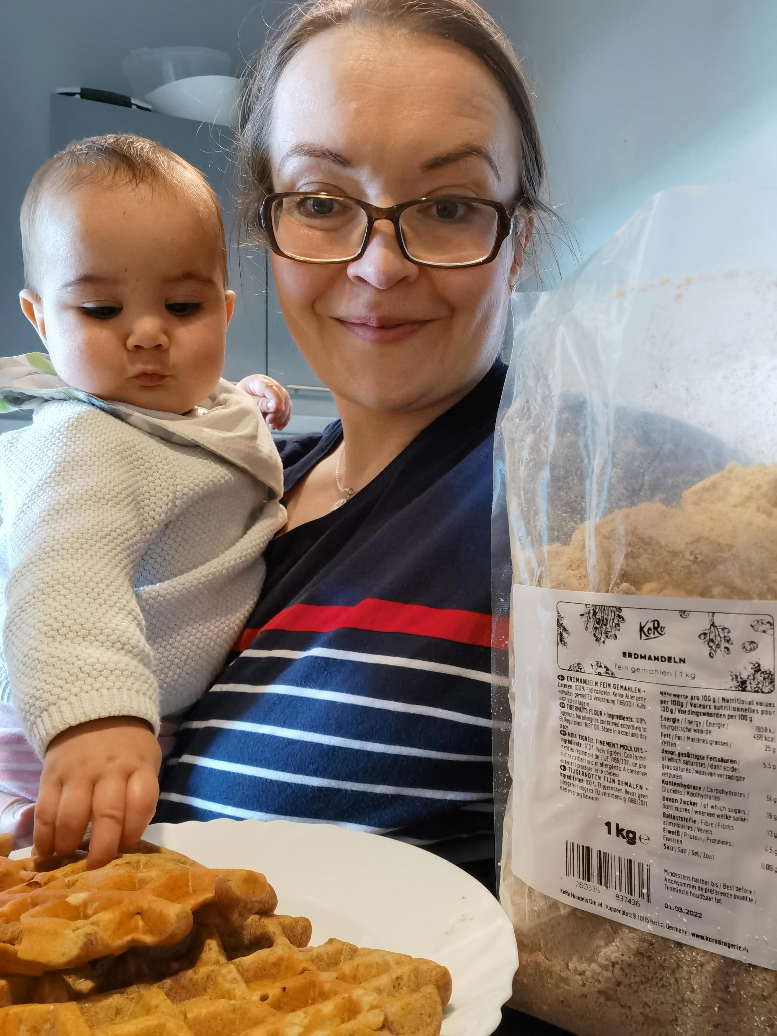 une femme tient un bébé devant une assiette de gaufres
