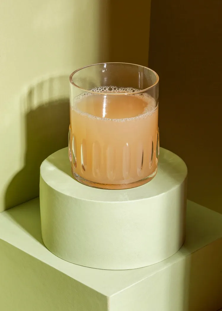 ein Glas mit einem Getränk darin sitzt auf einem grünen Sockel