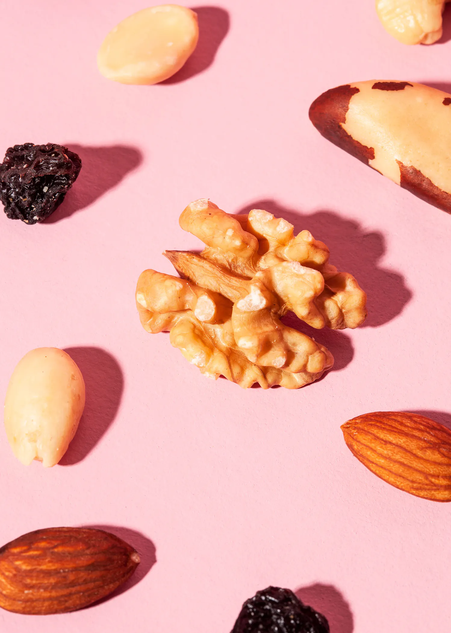 un tas de noix et de fruits séchés sur fond rose