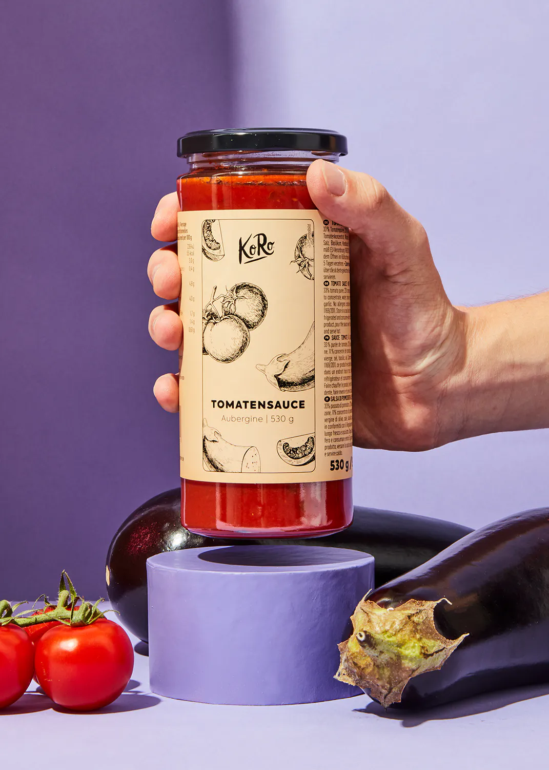 une personne tient une bouteille de sauce tomate aubergine