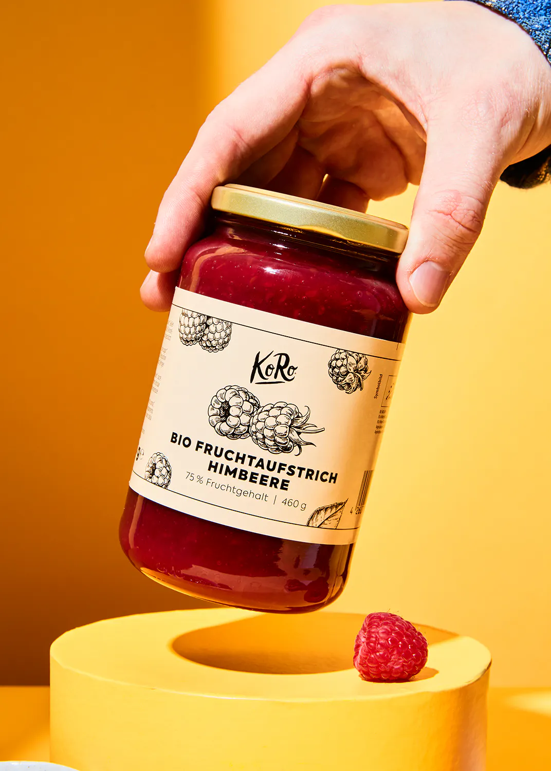 une personne tient un pot de confiture de framboise bio