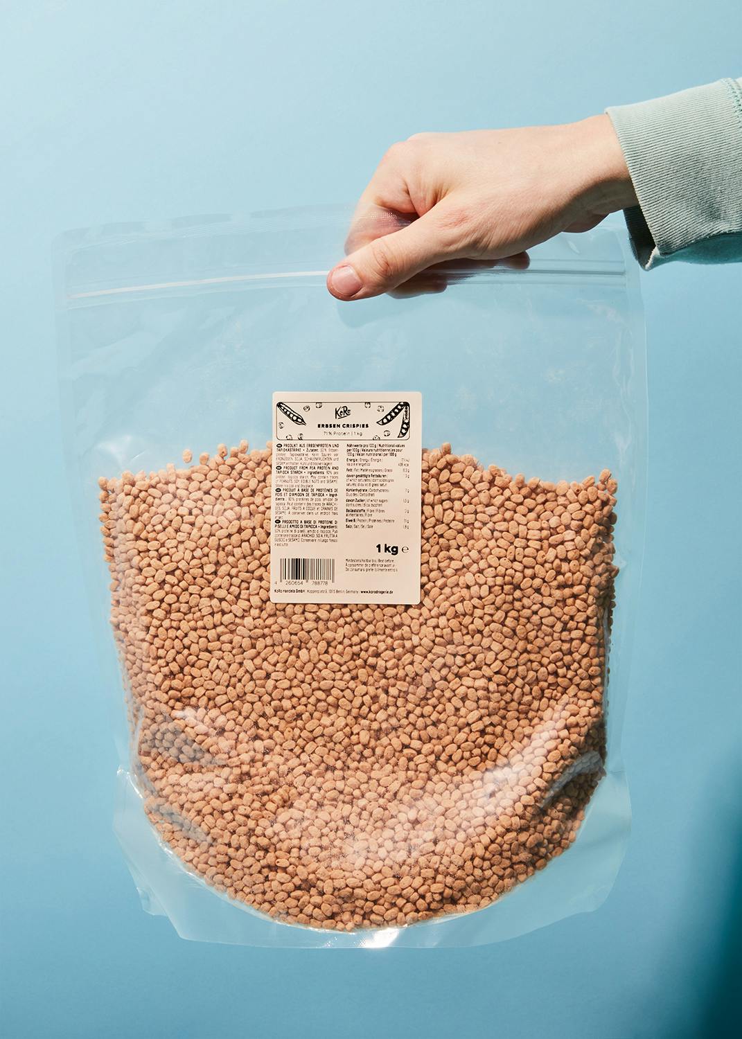 une personne tient un sac en plastique rempli de haricots verts