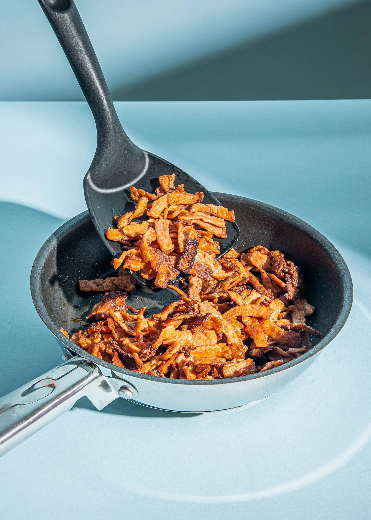 a spatula is being used to stir fried food in a frying pan