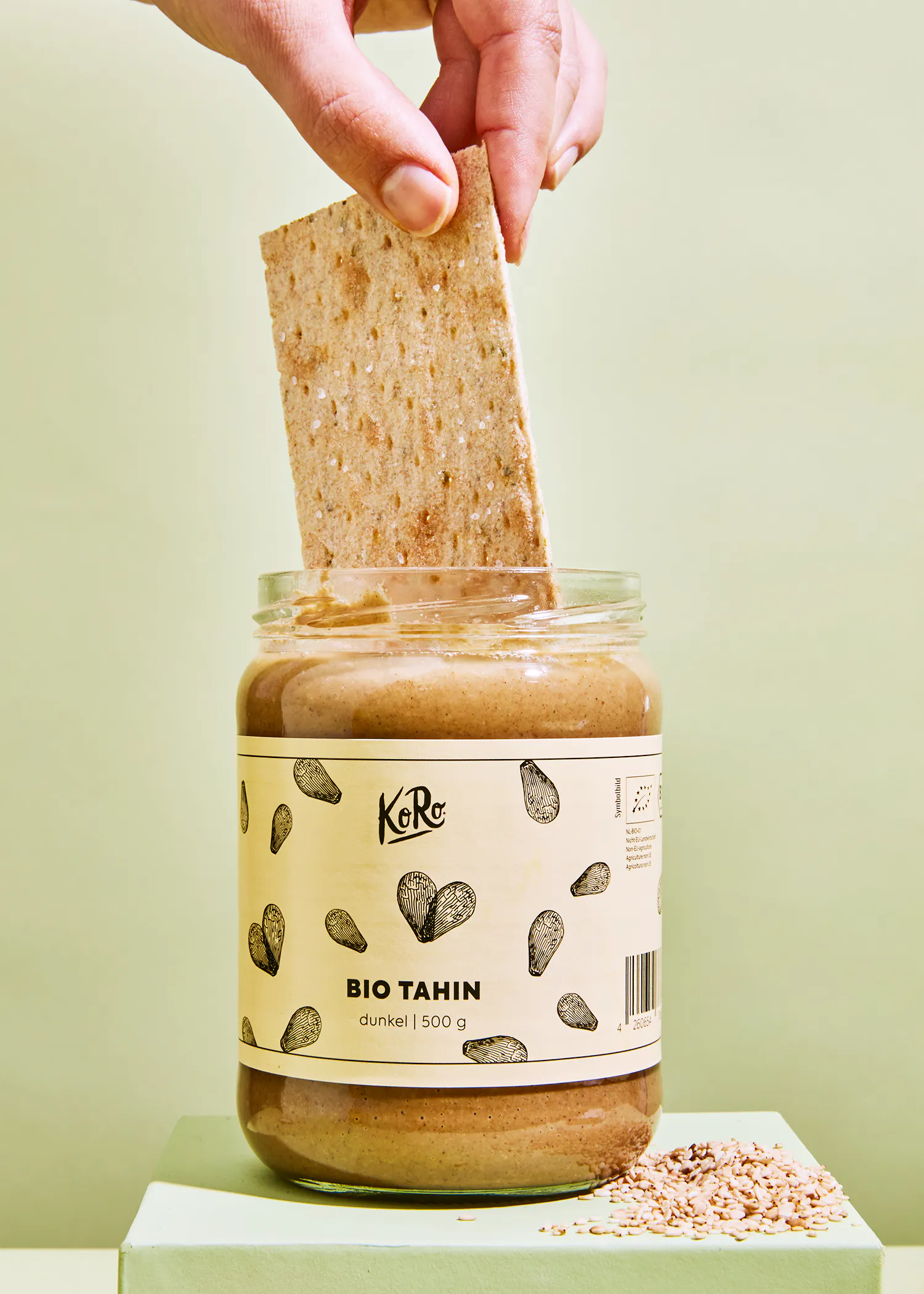 a person is dipping a piece of bread into a jar of bio tahin
