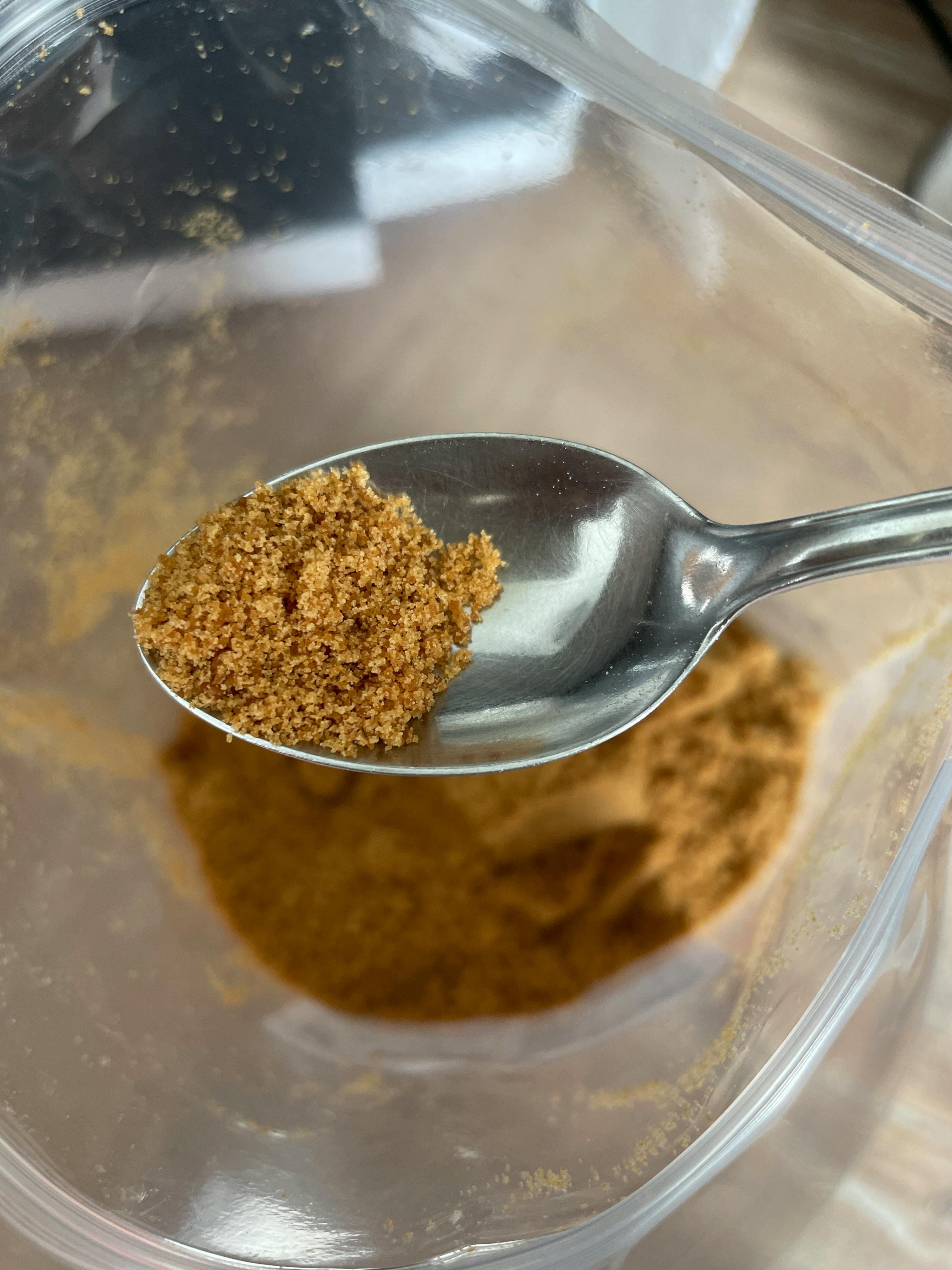 una cucchiaio di zucchero di canna è in cima a una ciotola di zucchero di canna