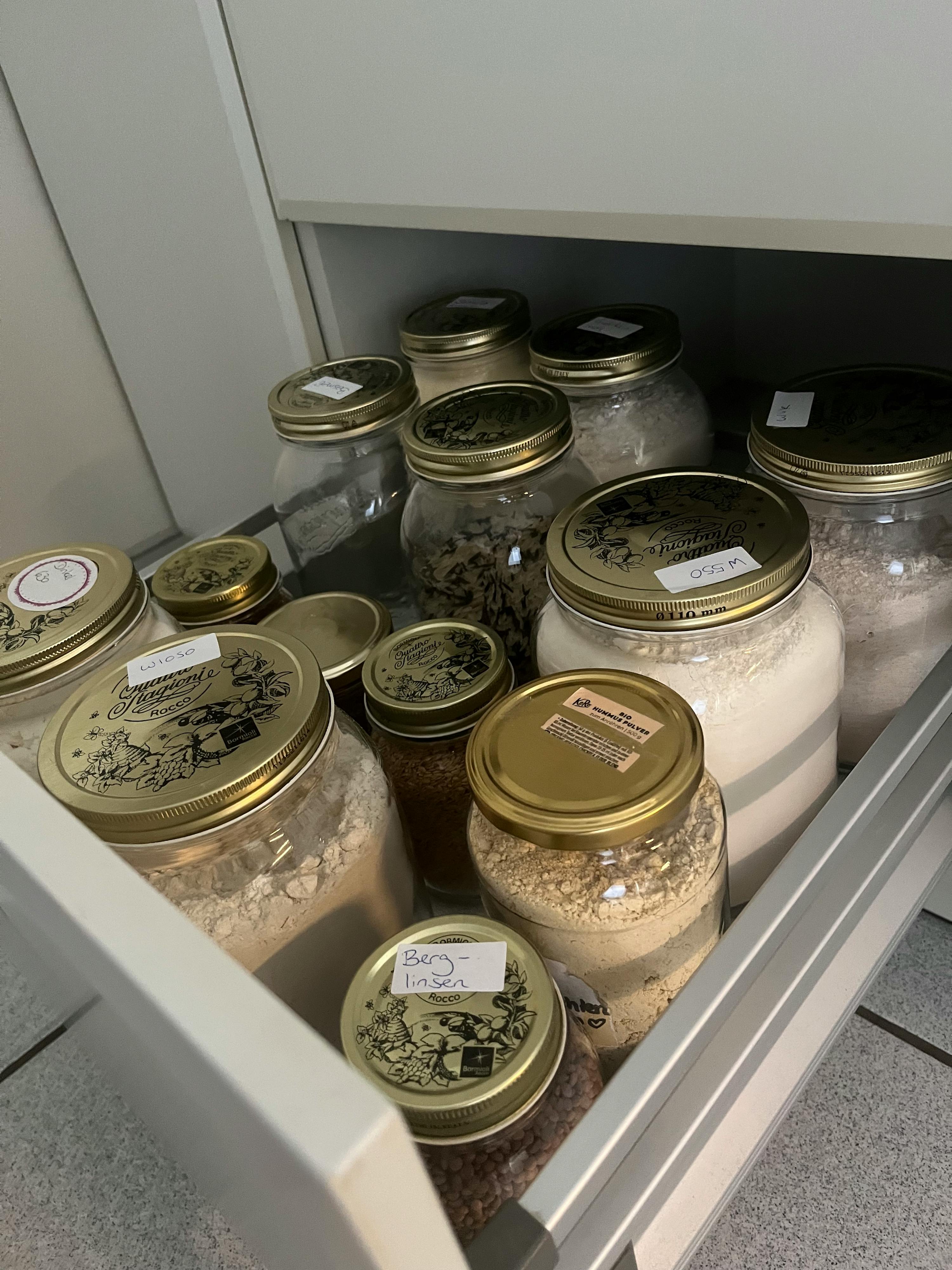 un tiroir rempli de bocaux de nourriture dont l' un a l' étiquette de farine