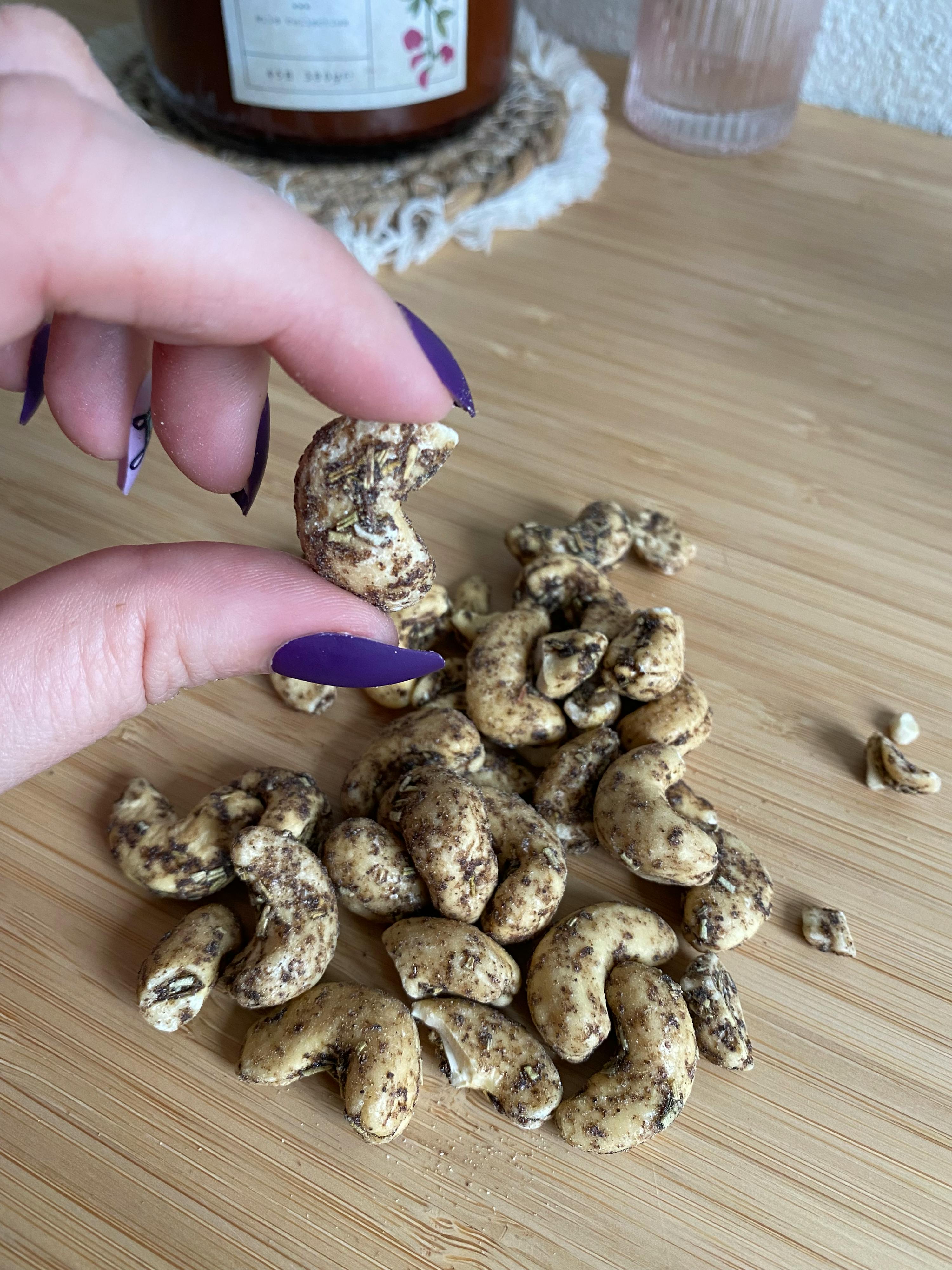 una persona con le unghie viola tiene in mano un mucchio di anacardi