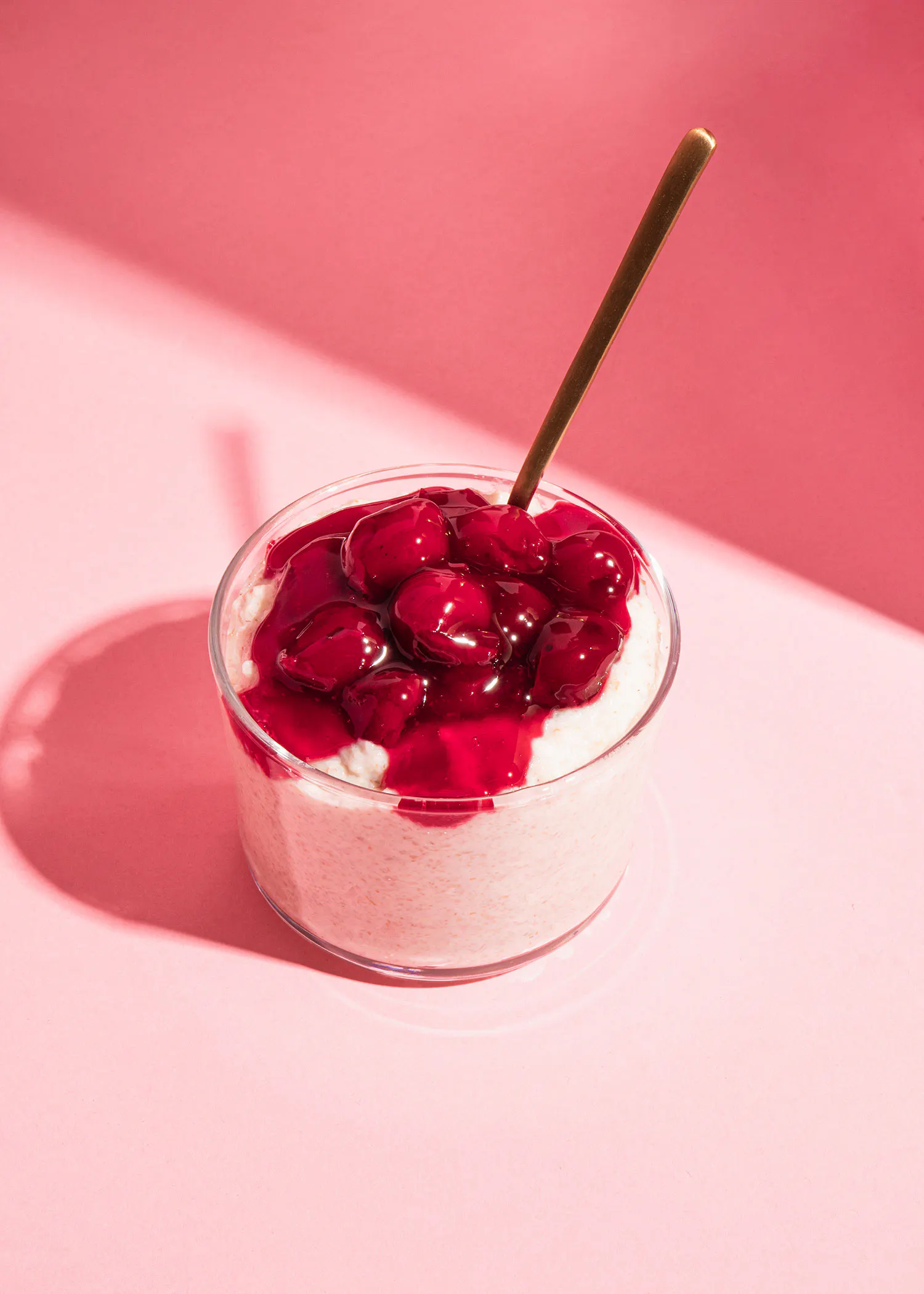 un bol en verre rempli de crème et de cerises avec une cuillère