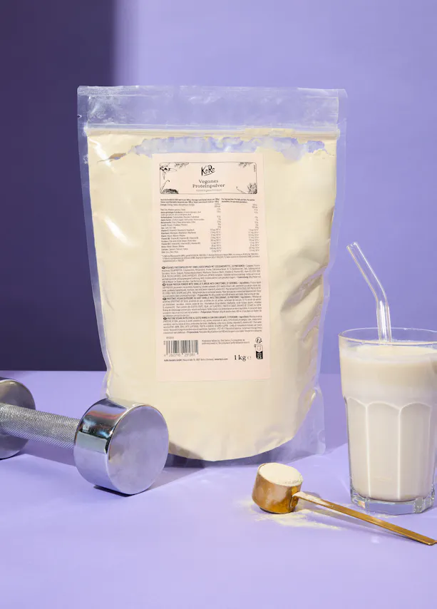 un sac de poudre de protéines végétales est posé à côté d' un verre de lait et d' un haltère