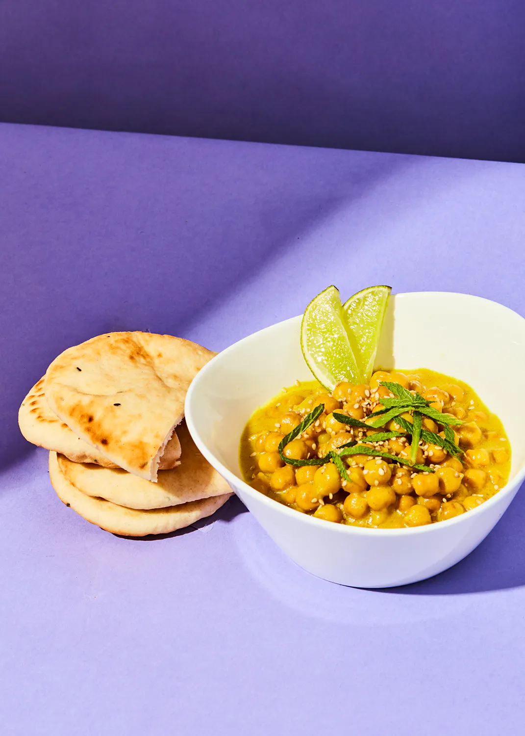 a bowl of food with chickpeas and a slice of lime