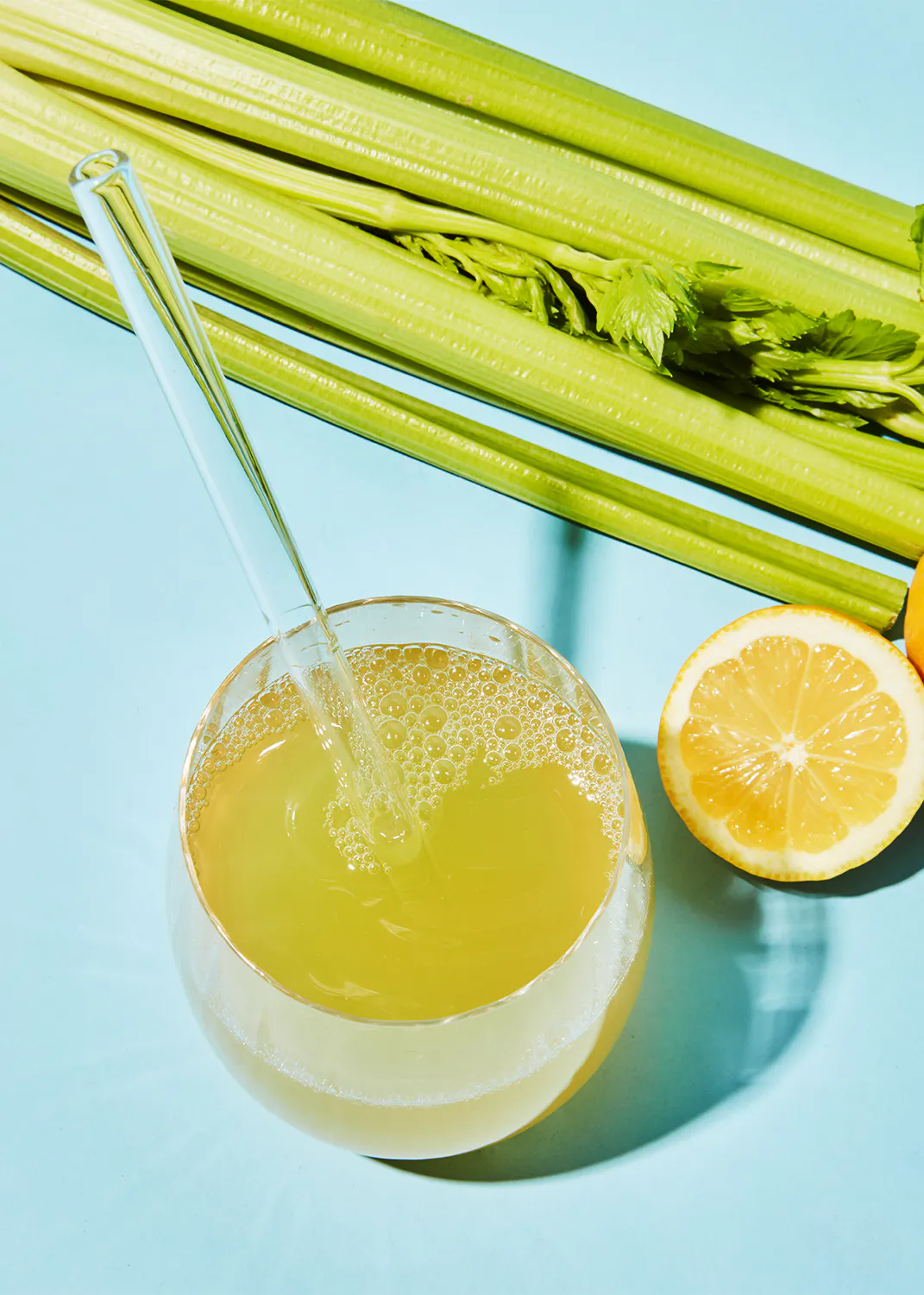 un vaso de jugo de limón y apio con una pajita