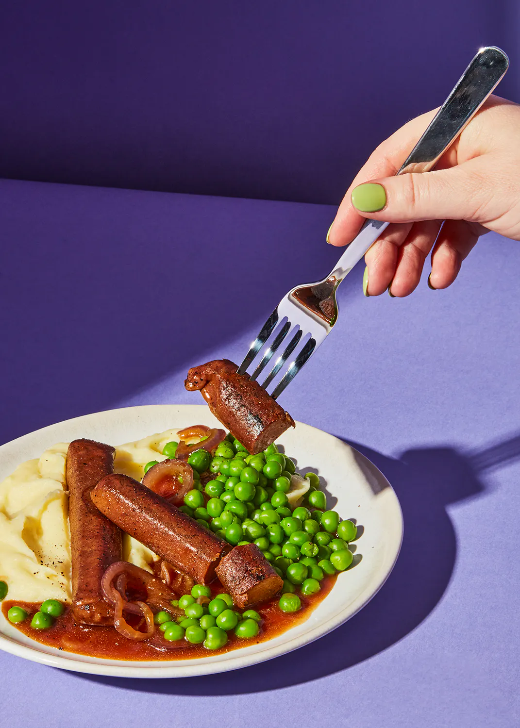 une personne tient une fourchette sur une assiette de nourriture avec des pois et des pommes de terre