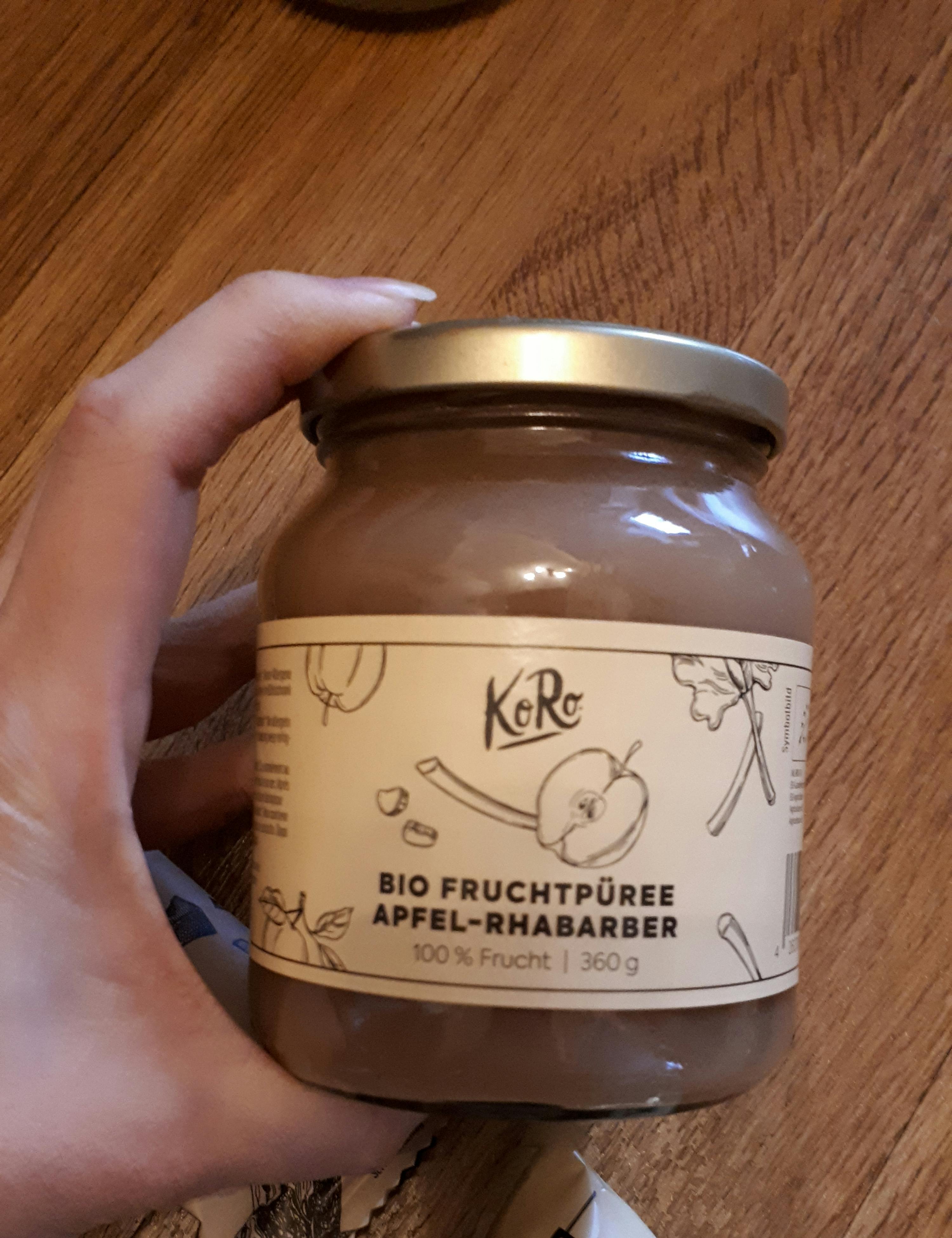 une personne tient un bocal de purée de fruits bio