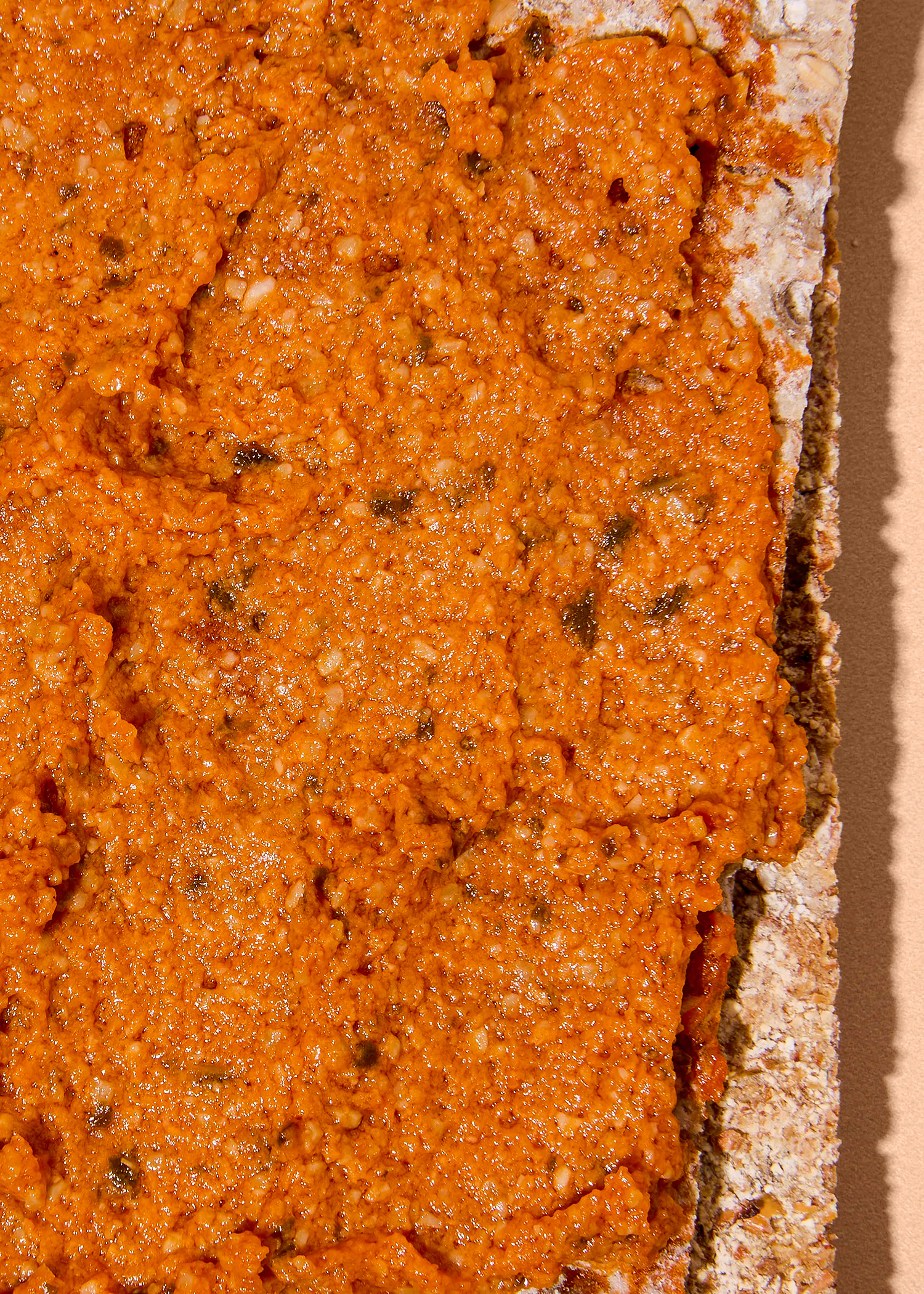 gros plan sur une tartine de pain croustillant recouverte d'une épaisse couche de tapenade ou de crème de tomates séchées orange.
