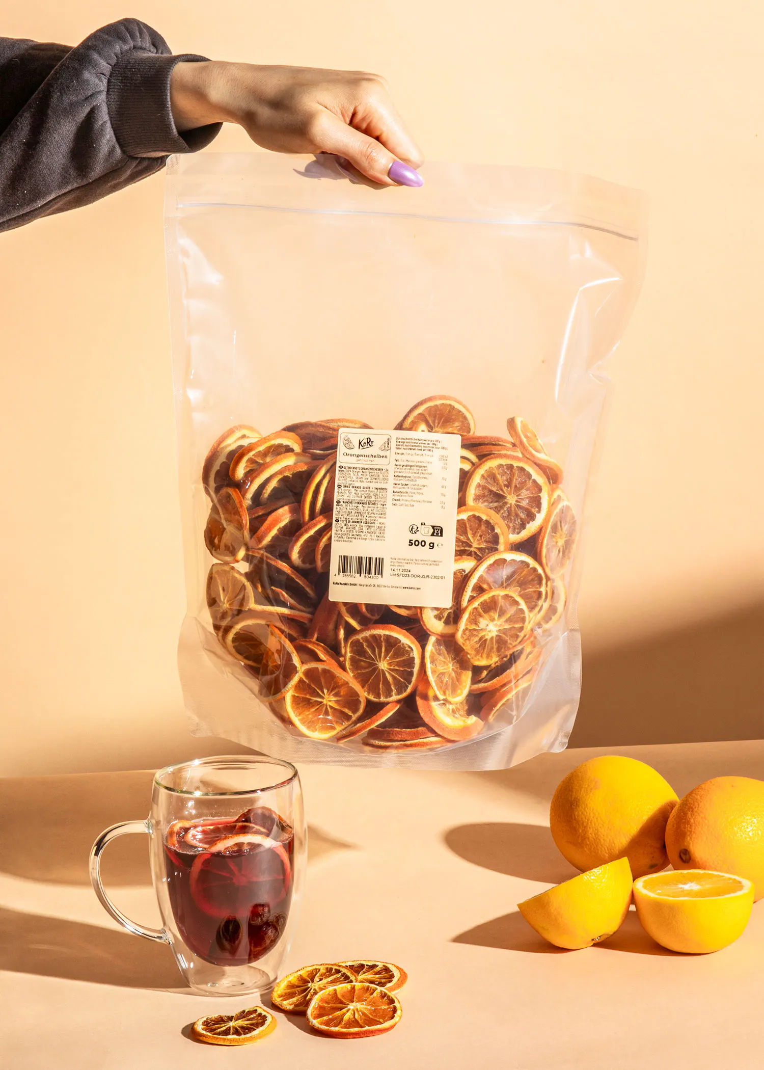 une personne tient un sac de tranches d' orange séchées à côté d' une tasse de thé