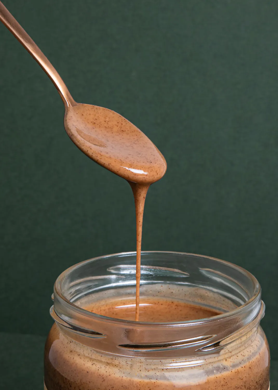 a jar of peanut butter is being poured from a spoon