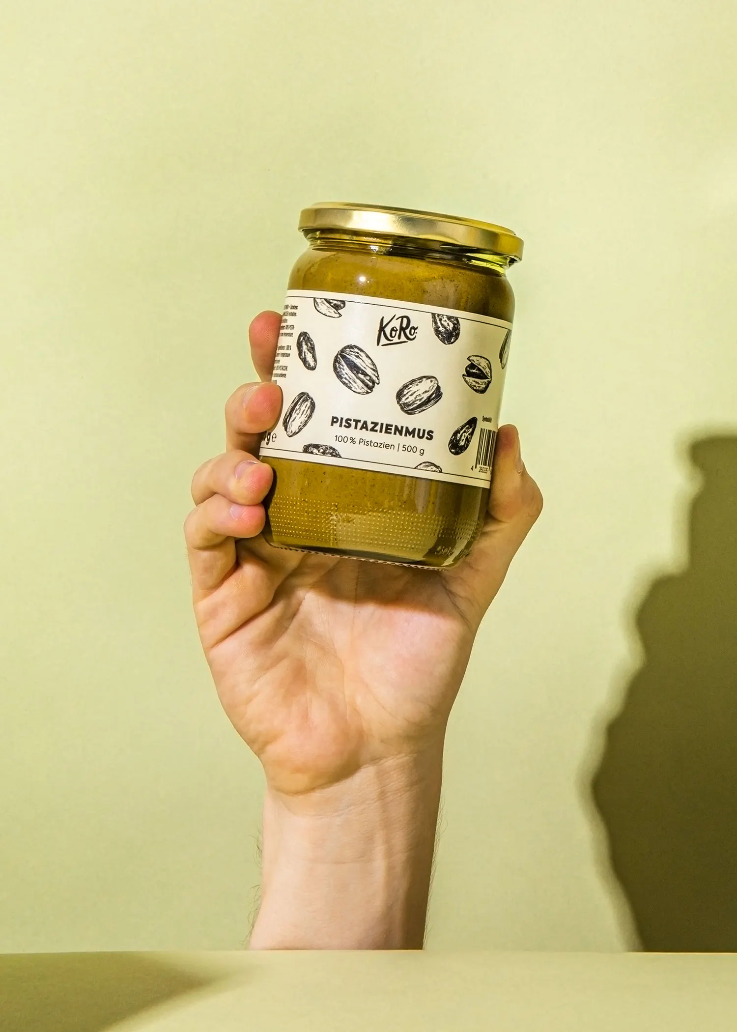 une personne tient un bocal de pistazienmus dans sa main