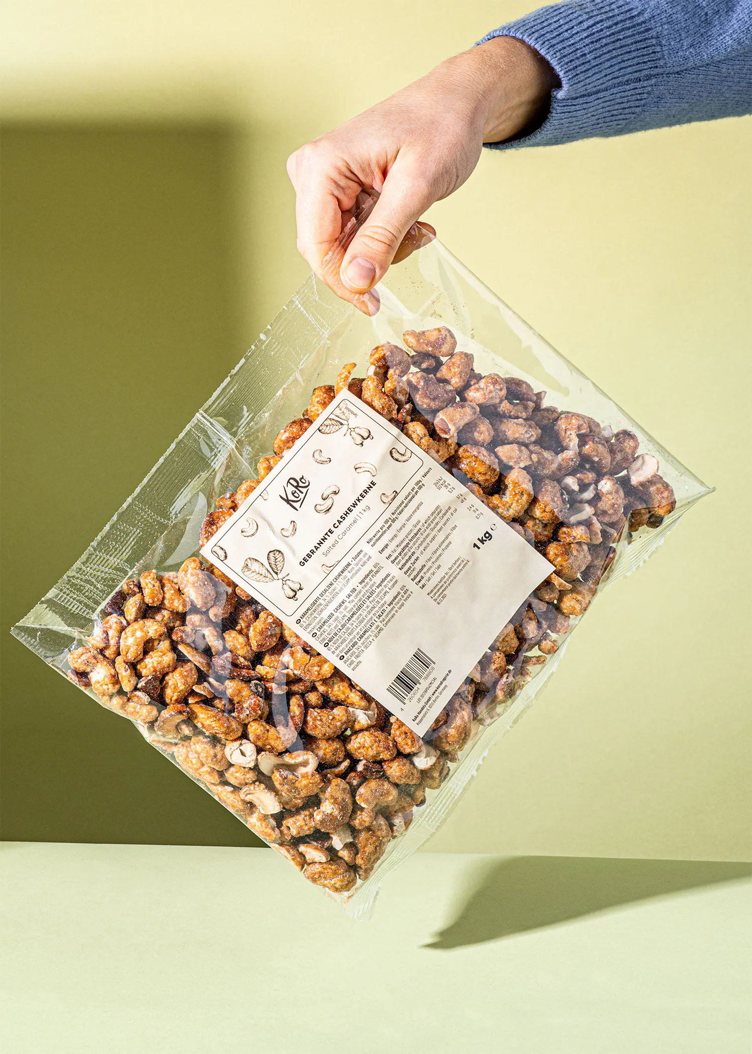 a person is holding a bag of caramelized cashews
