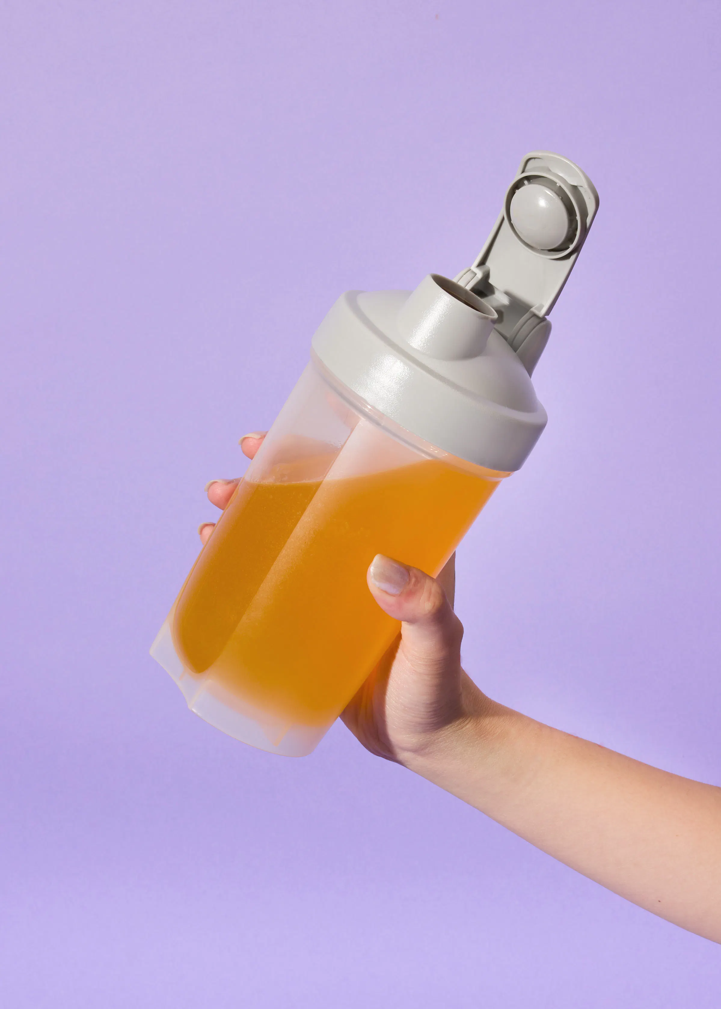 a person is holding a shaker with a yellow liquid in it