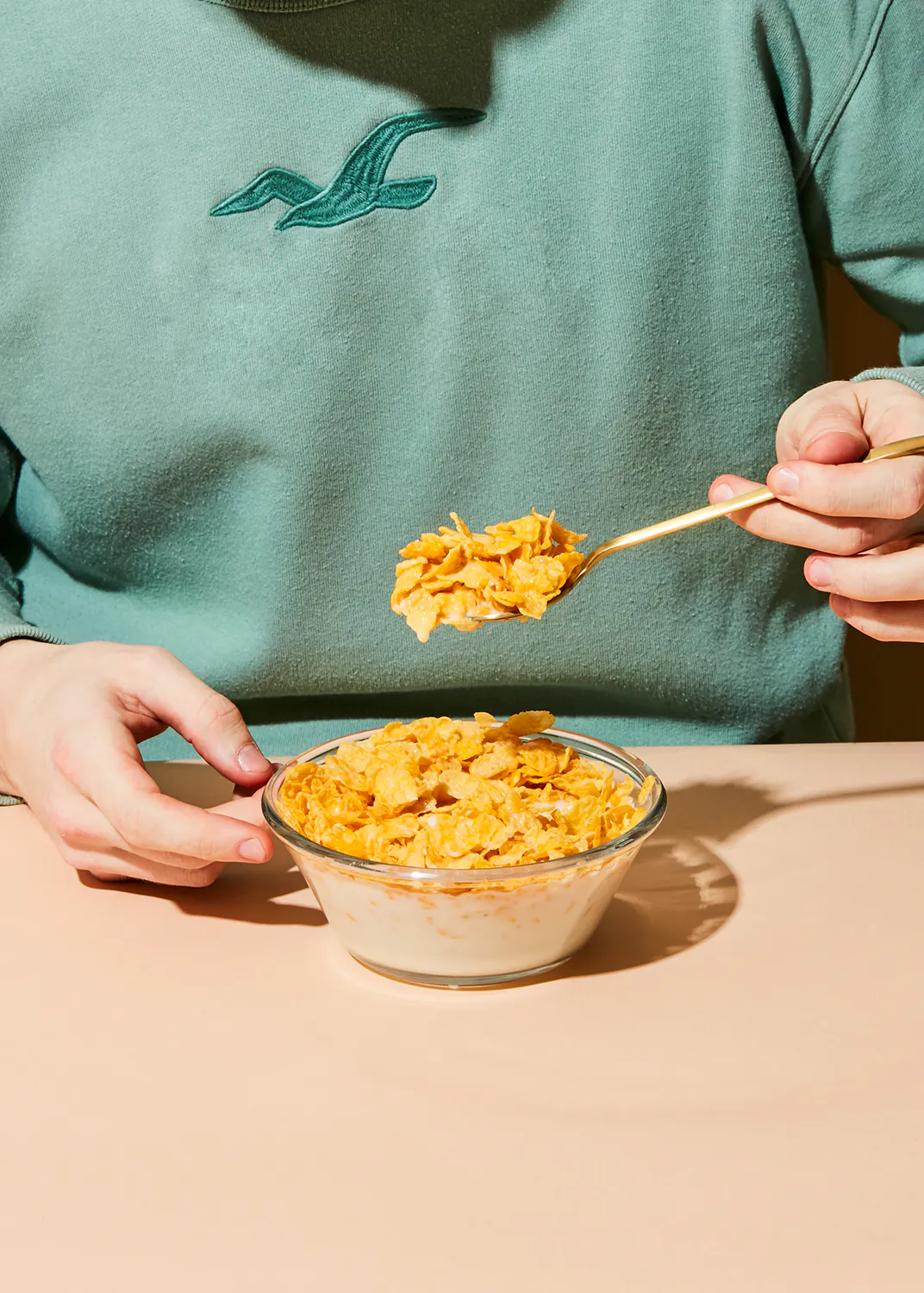 une personne porte un sweat-shirt hollister mangeant des céréales avec une cuillère