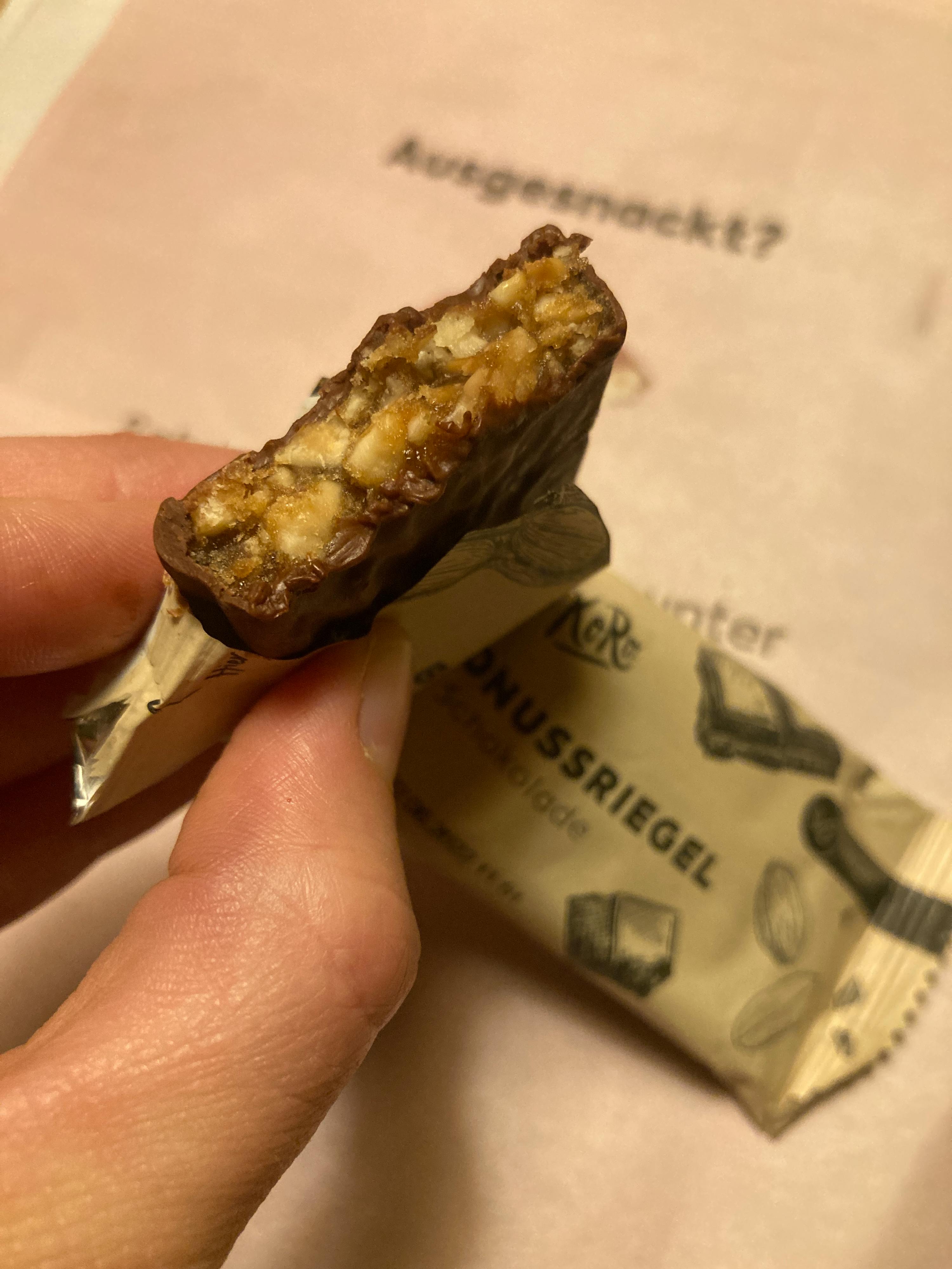 une personne tient une barre de chocolat avec une bouchée sortie