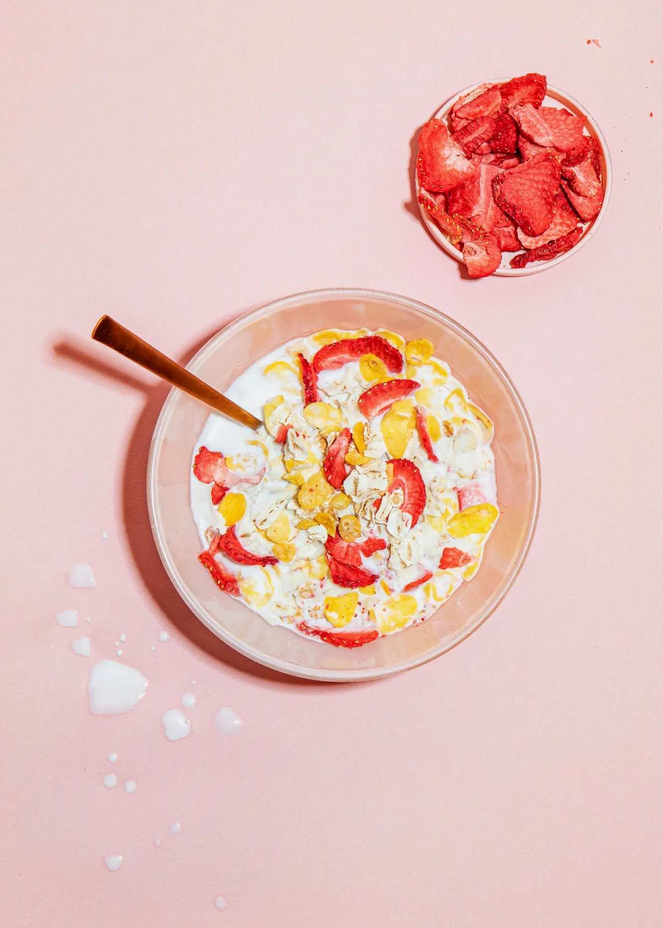 a bowl of cereal with milk and strawberries next to a plate of strawberries