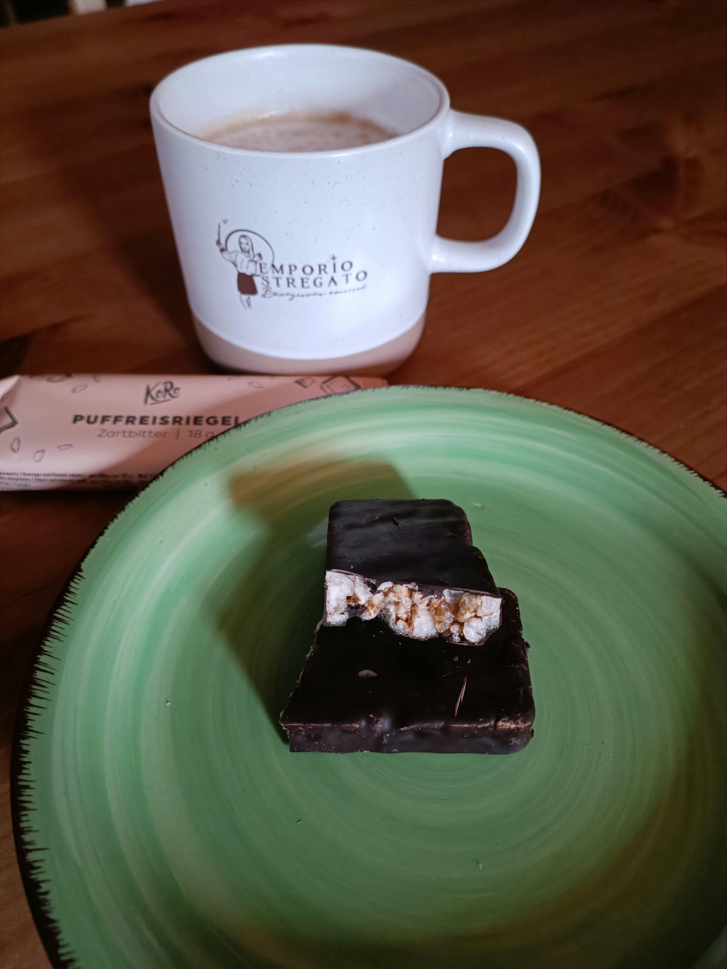 un piatto verde con un pezzo di cioccolato e una tazza di caffè