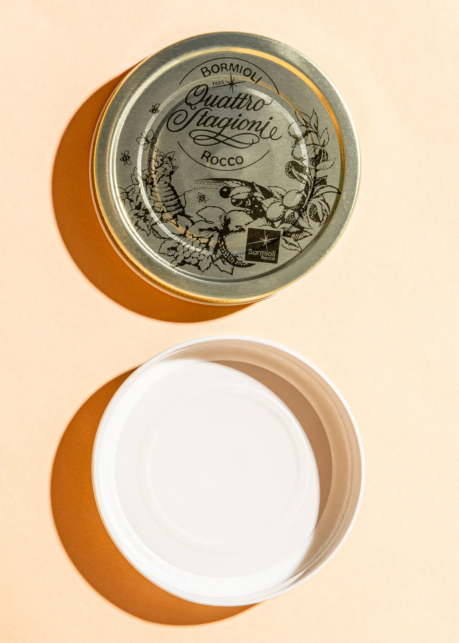 ein weißer Teller steht neben einem silbernen Deckel mit der Aufschrift bormioli