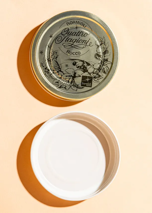 ein weißer Teller steht neben einem silbernen Deckel mit der Aufschrift bormioli