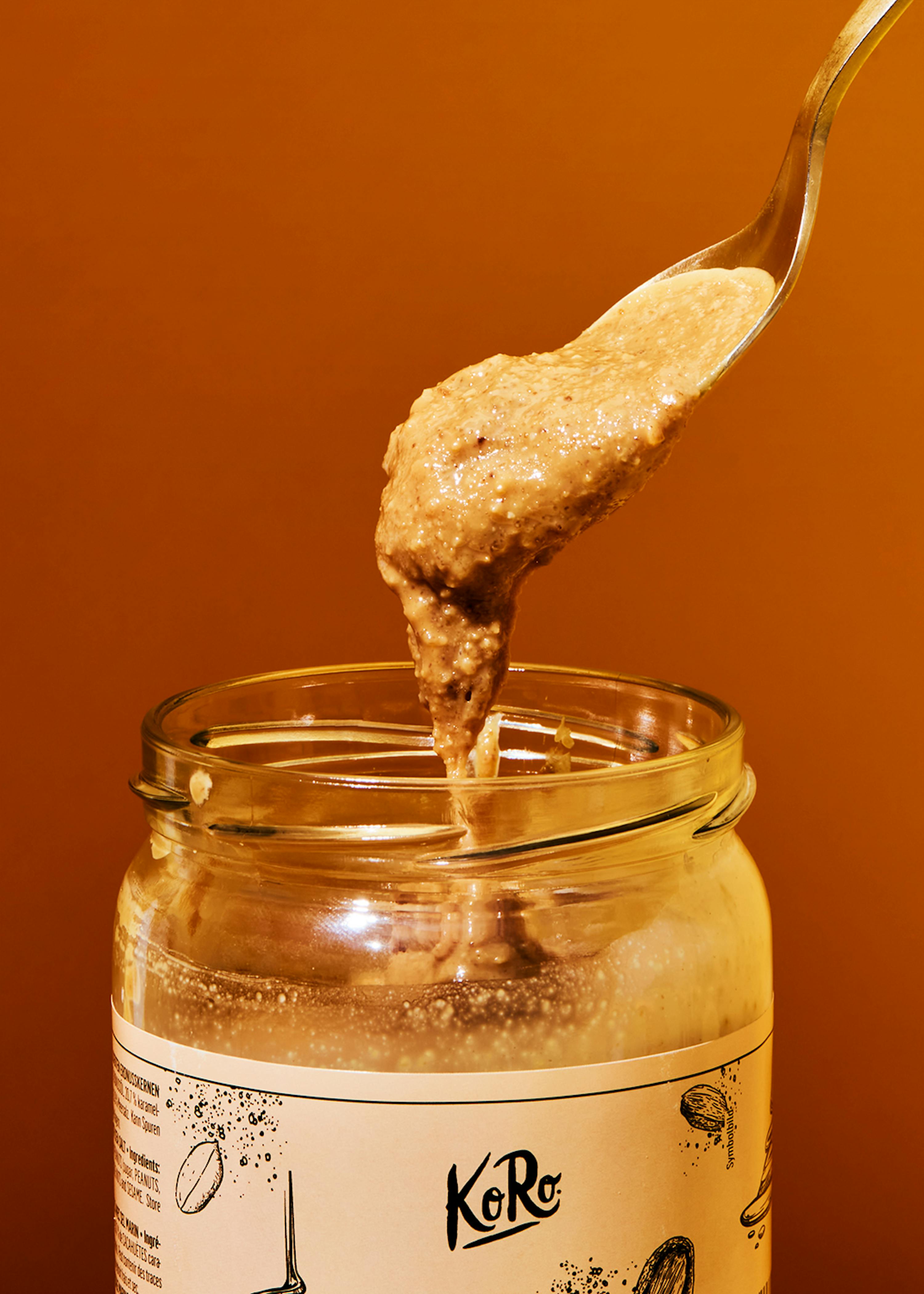 a jar of koro peanut butter is being poured into a spoon