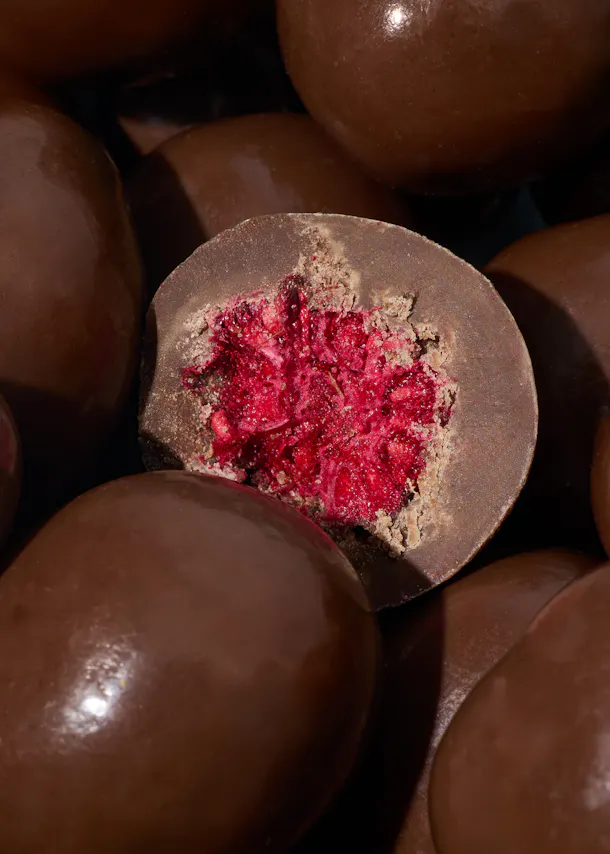 a close up of a chocolate covered item with a red center