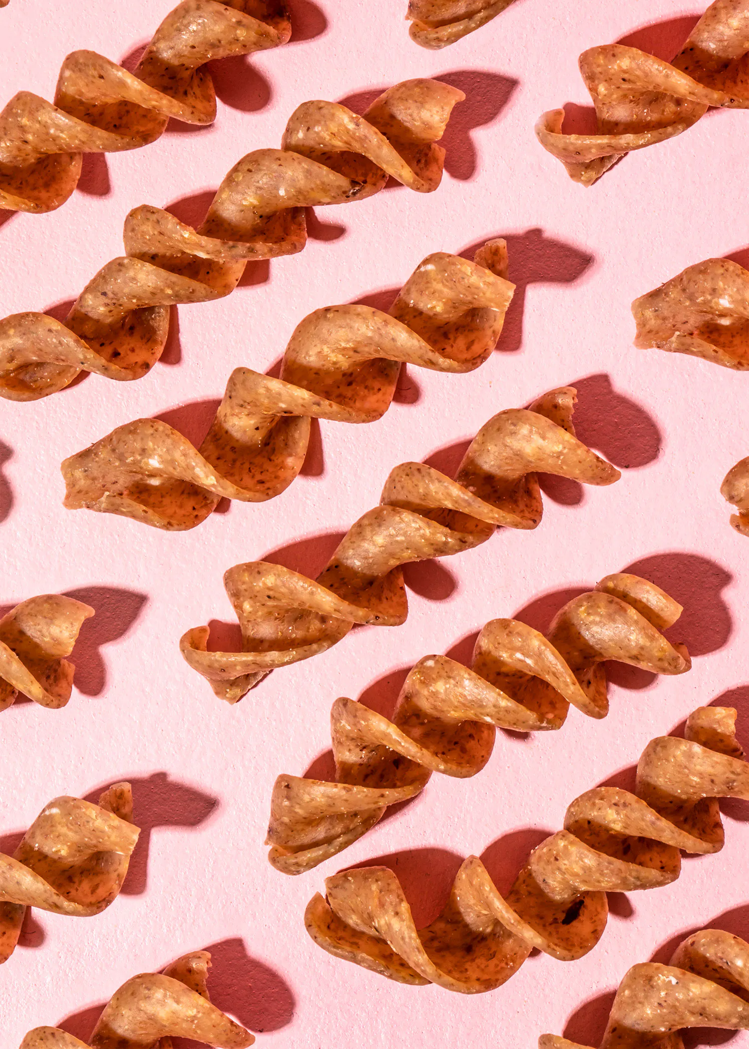 Eine Reihe von spiralförmigen Nudeln auf einem rosa Hintergrund