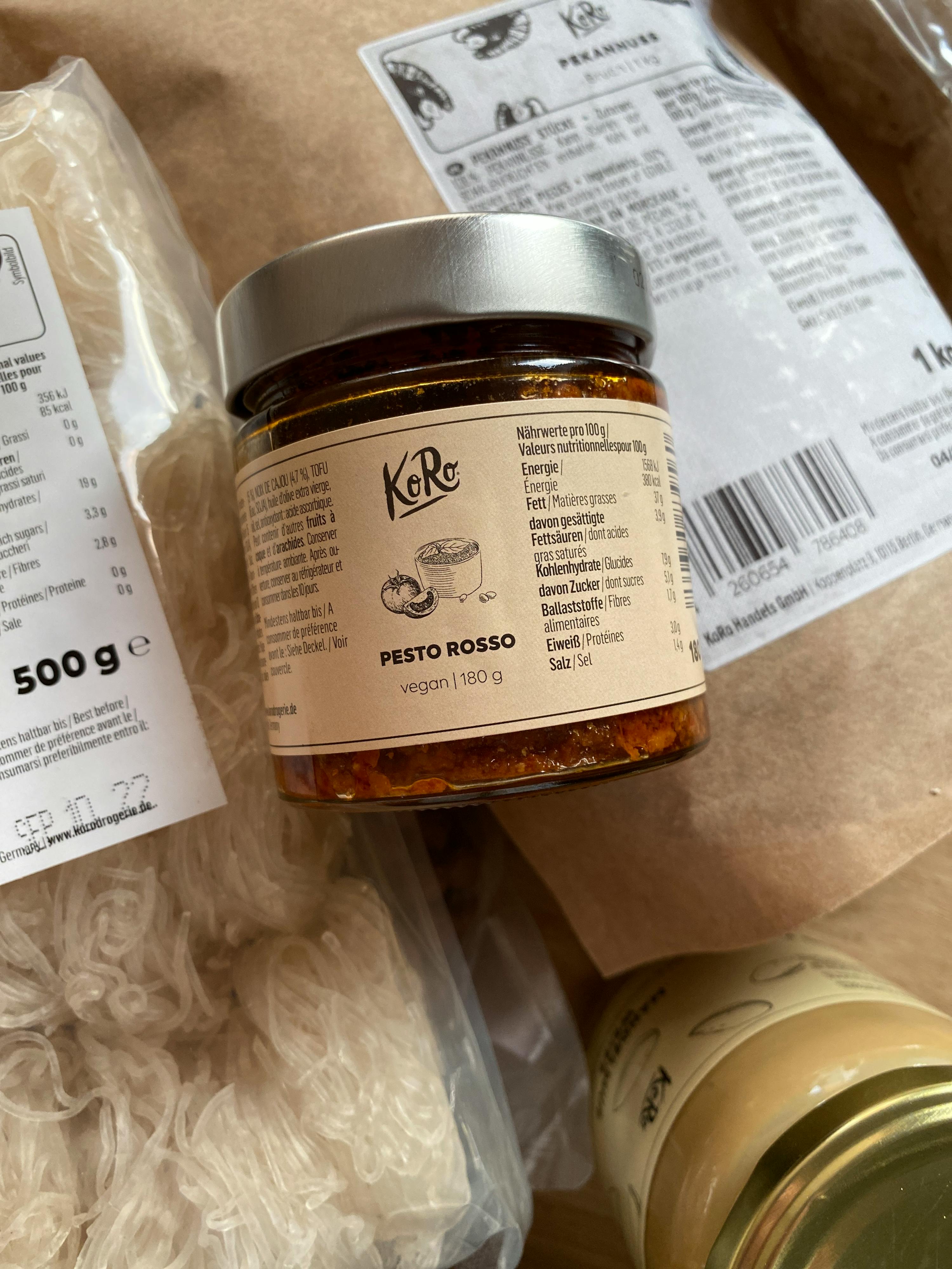 un barattolo di pesto rosso vegano è seduto accanto a un sacchetto di noodles