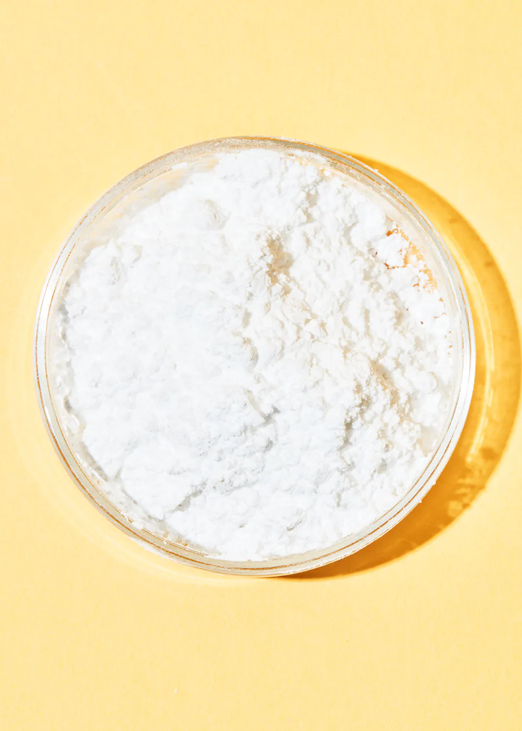 eine Petrischale mit weißem Pulver auf gelbem Hintergrund
