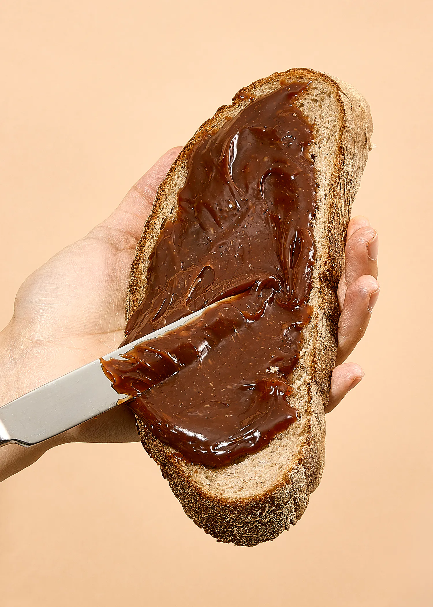 Eine Person hält ein Stück Brot mit Schokoladencreme und einem Messer