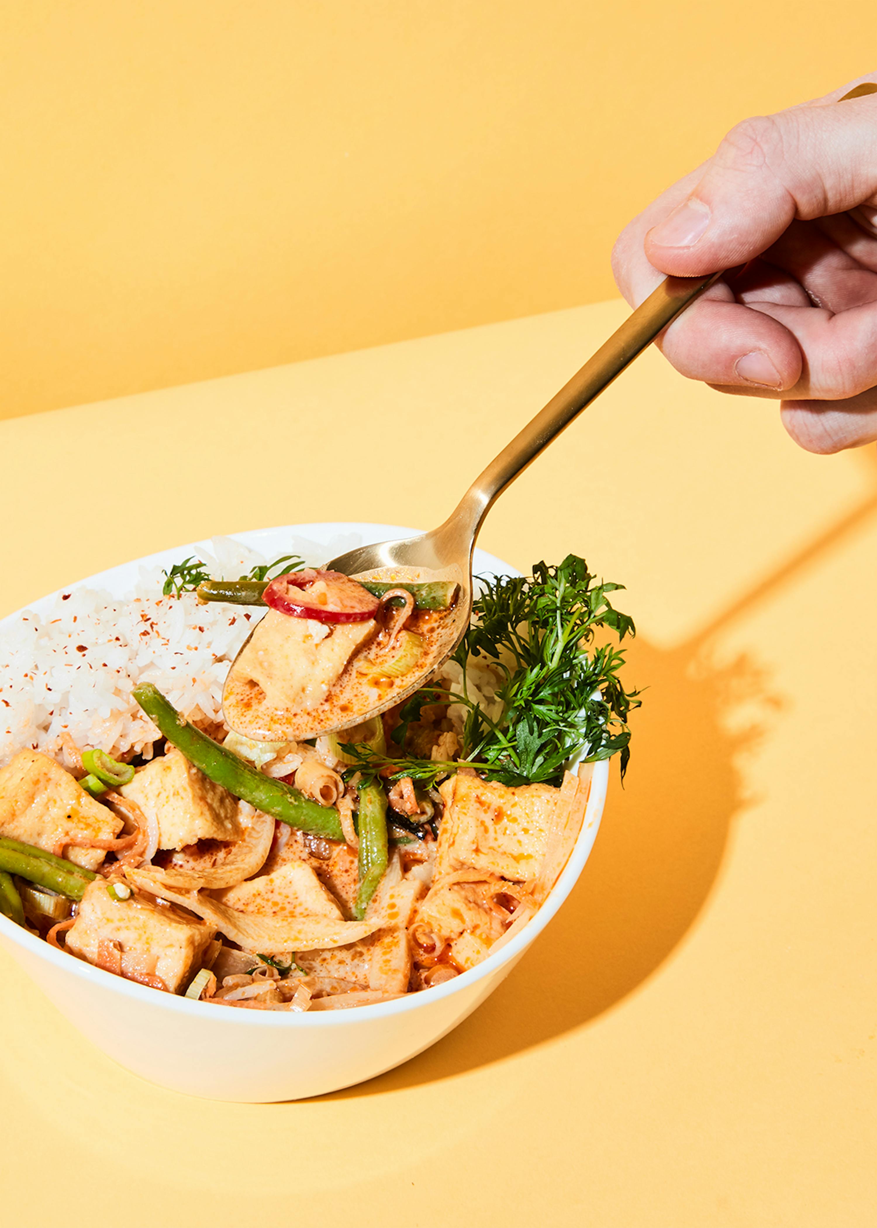 a person is holding a spoon over a bowl of food