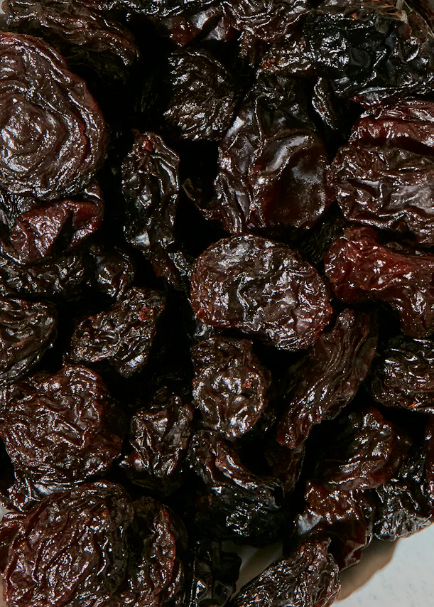 a pile of dried plums on a white surface