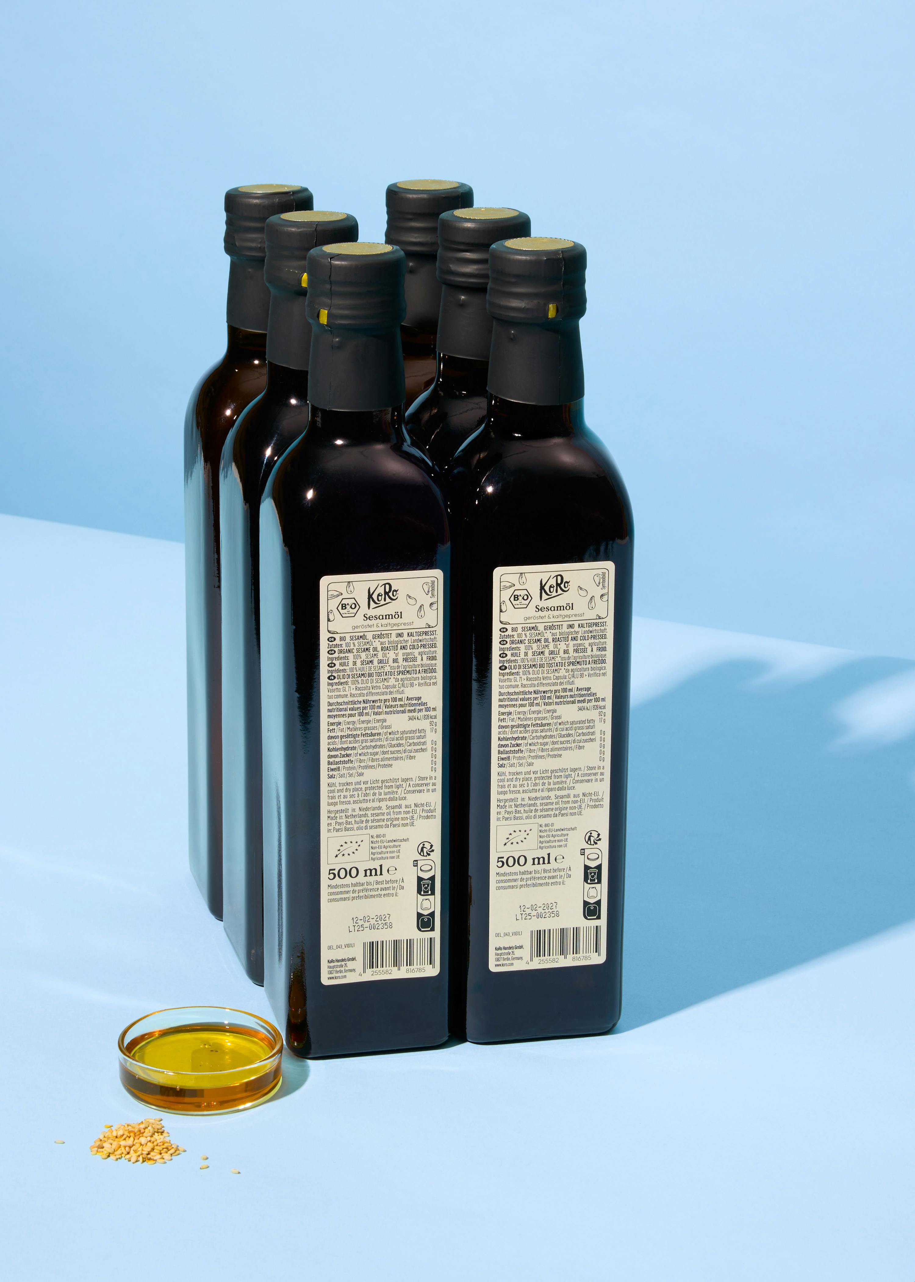 six bottles of kibb oil are lined up on a blue surface